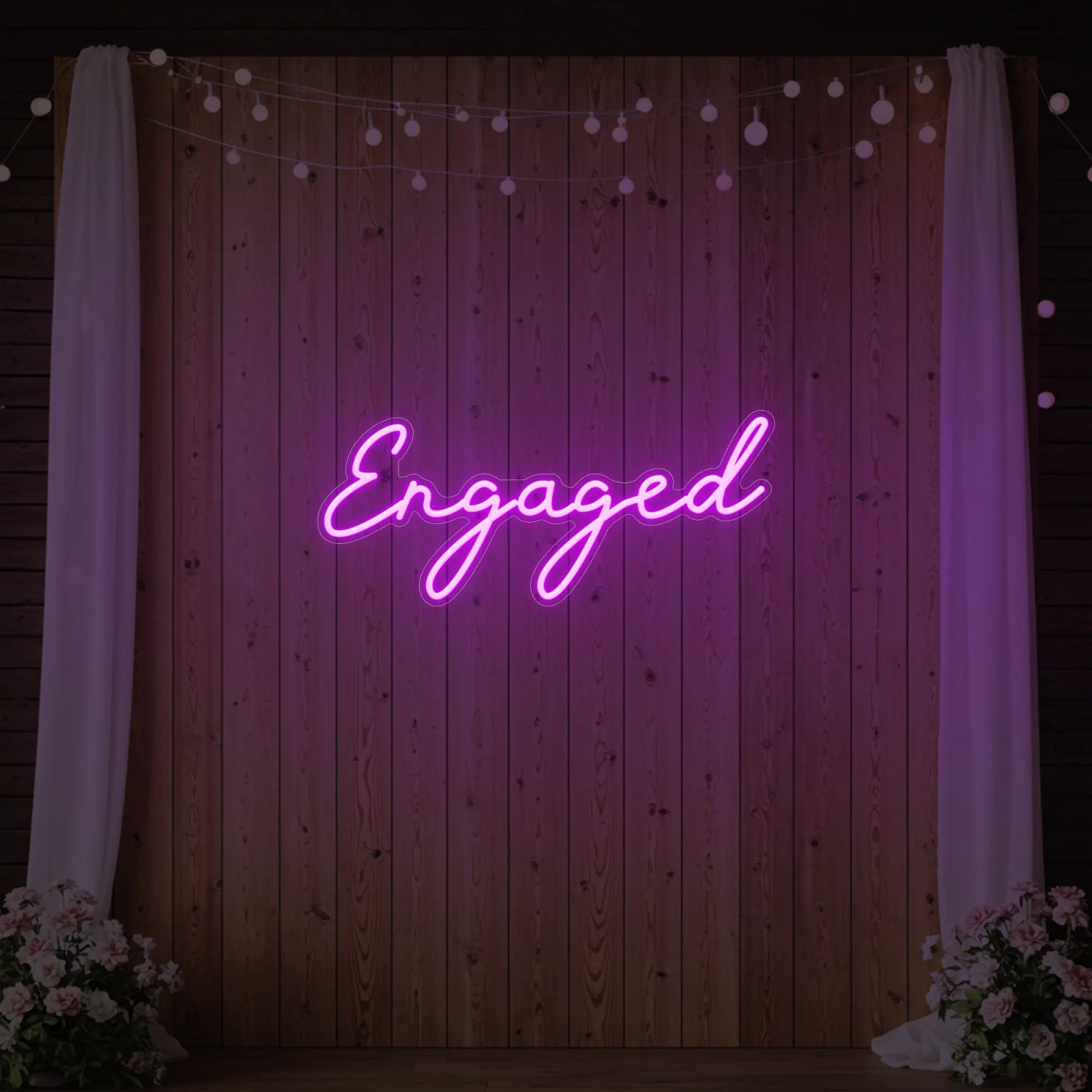 Photo of the 'Engaged' neon sign glowing in deep pink against a styled interior wall.