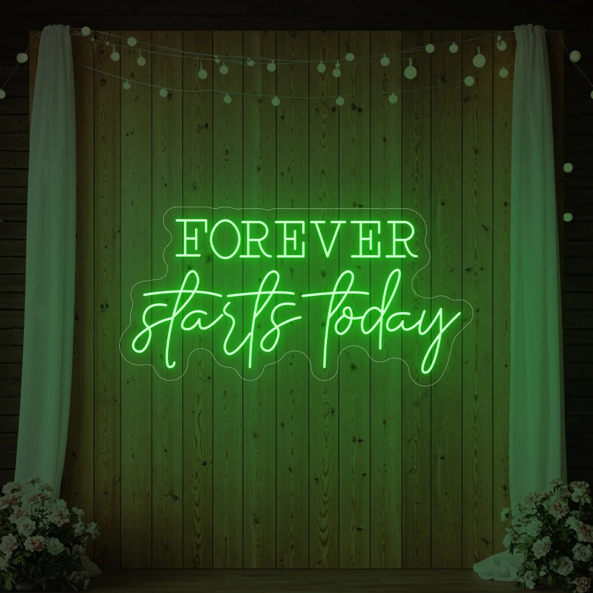 Photo of the 'Forever Starts Today' neon sign glowing in green against a styled interior wall.