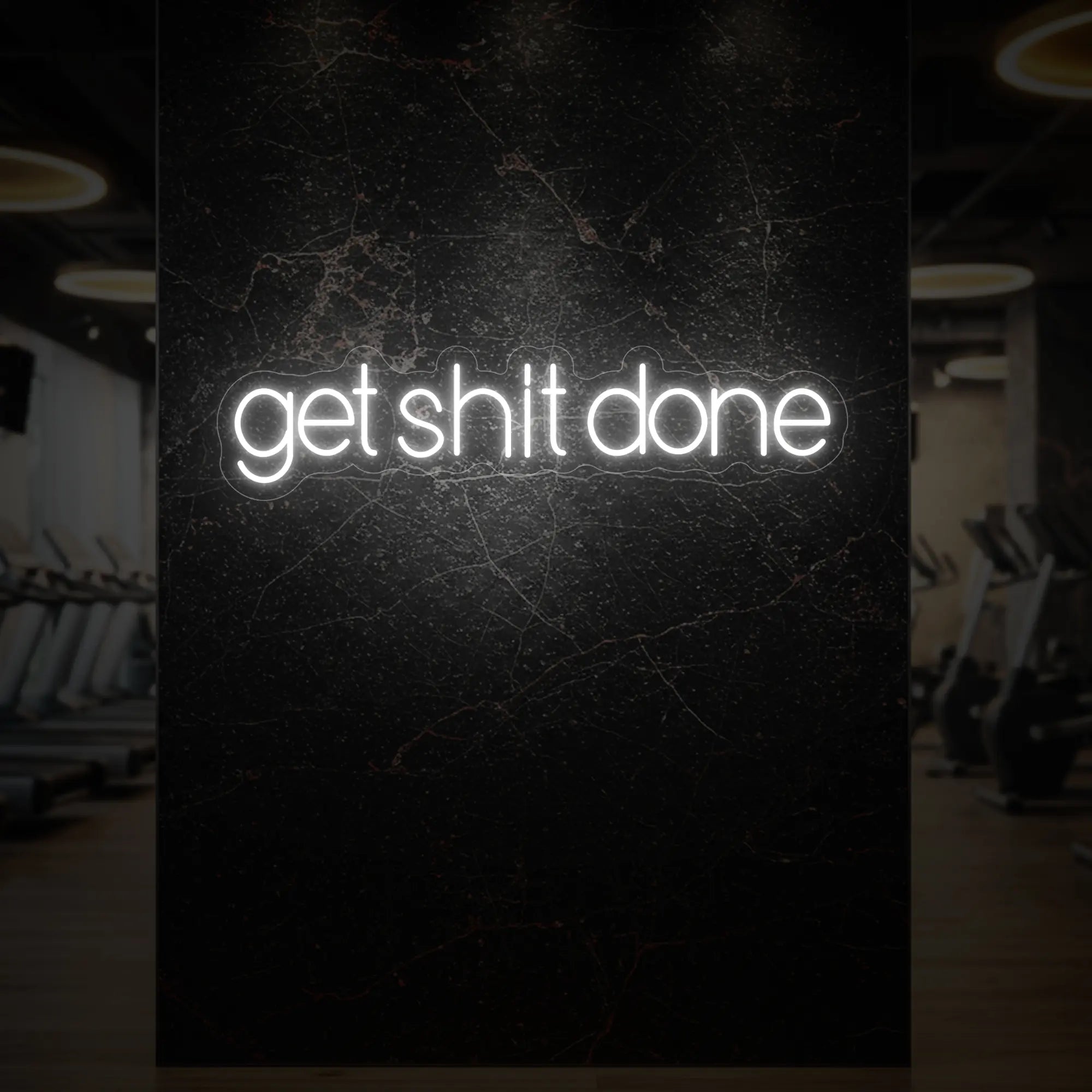 'Get Shit Done' neon sign glowing in cool white against a styled interior wall.