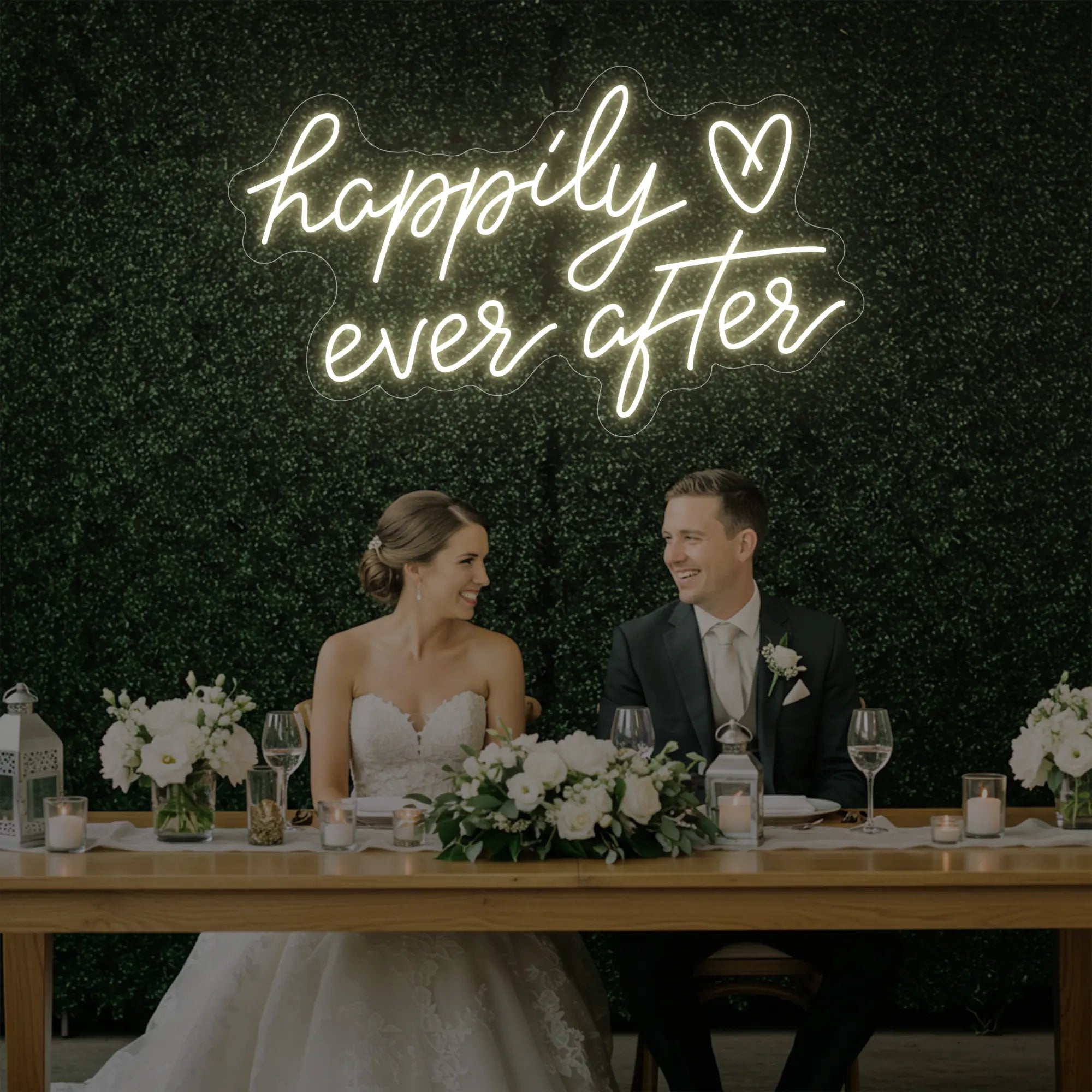 Photo of the 'Happily Ever After' neon sign glowing in warm white against a styled interior wall.