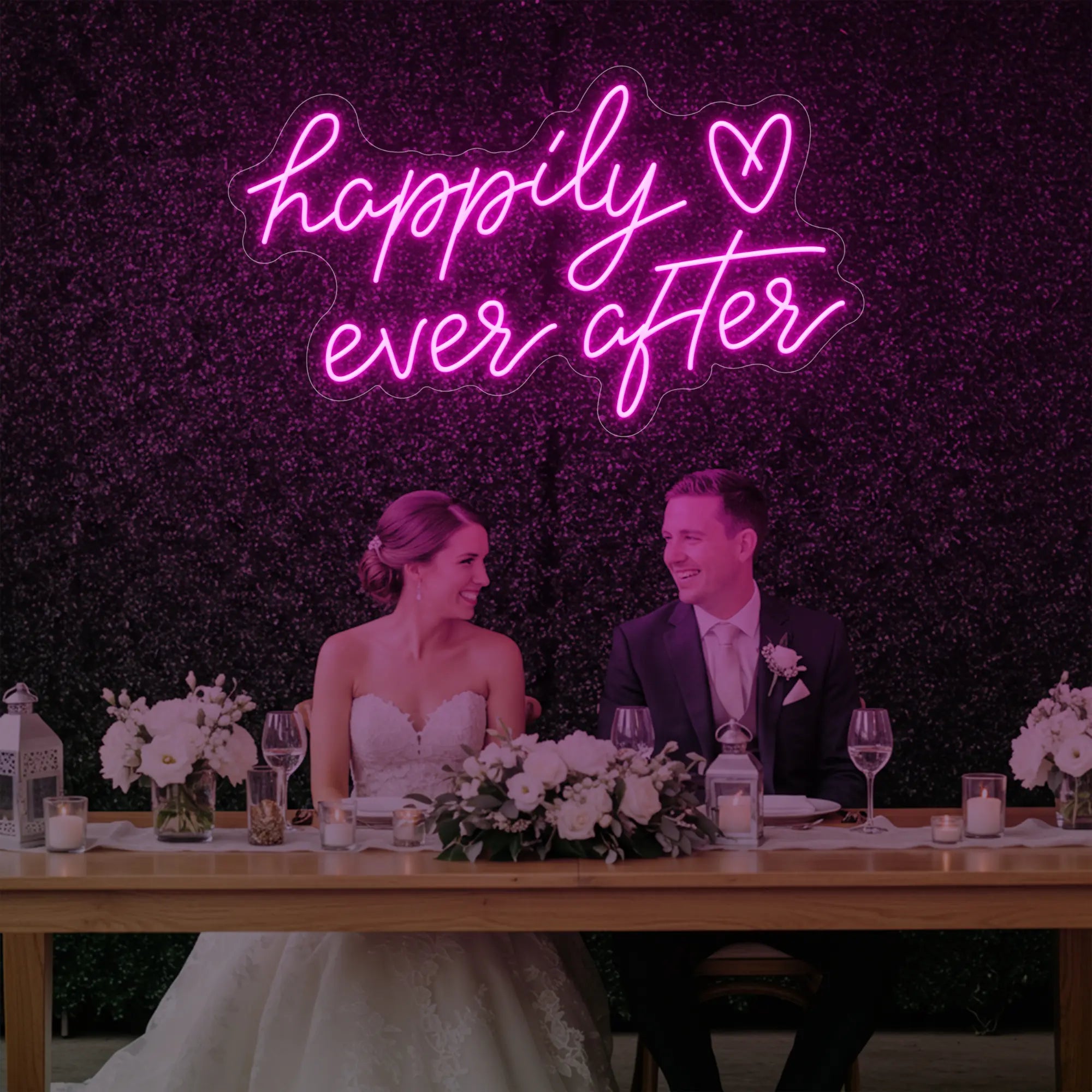 Photo of the 'Happily Ever After' neon sign glowing in light pink against a styled interior wall.