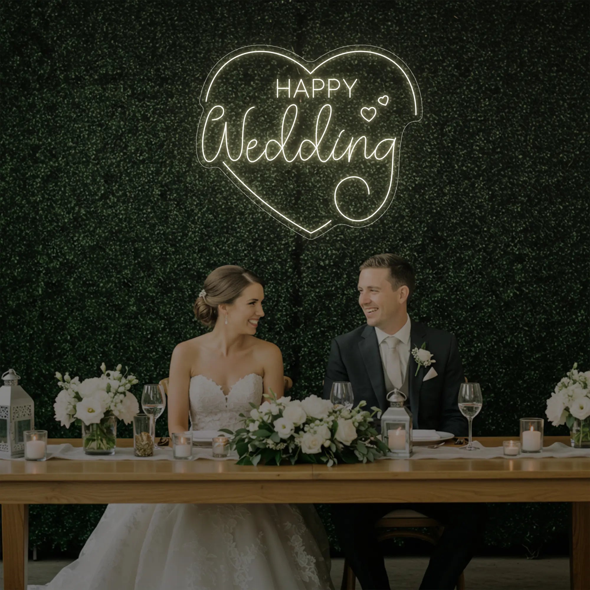 Photo of the 'Happy Wedding' neon sign glowing in warm white against a styled interior wall.