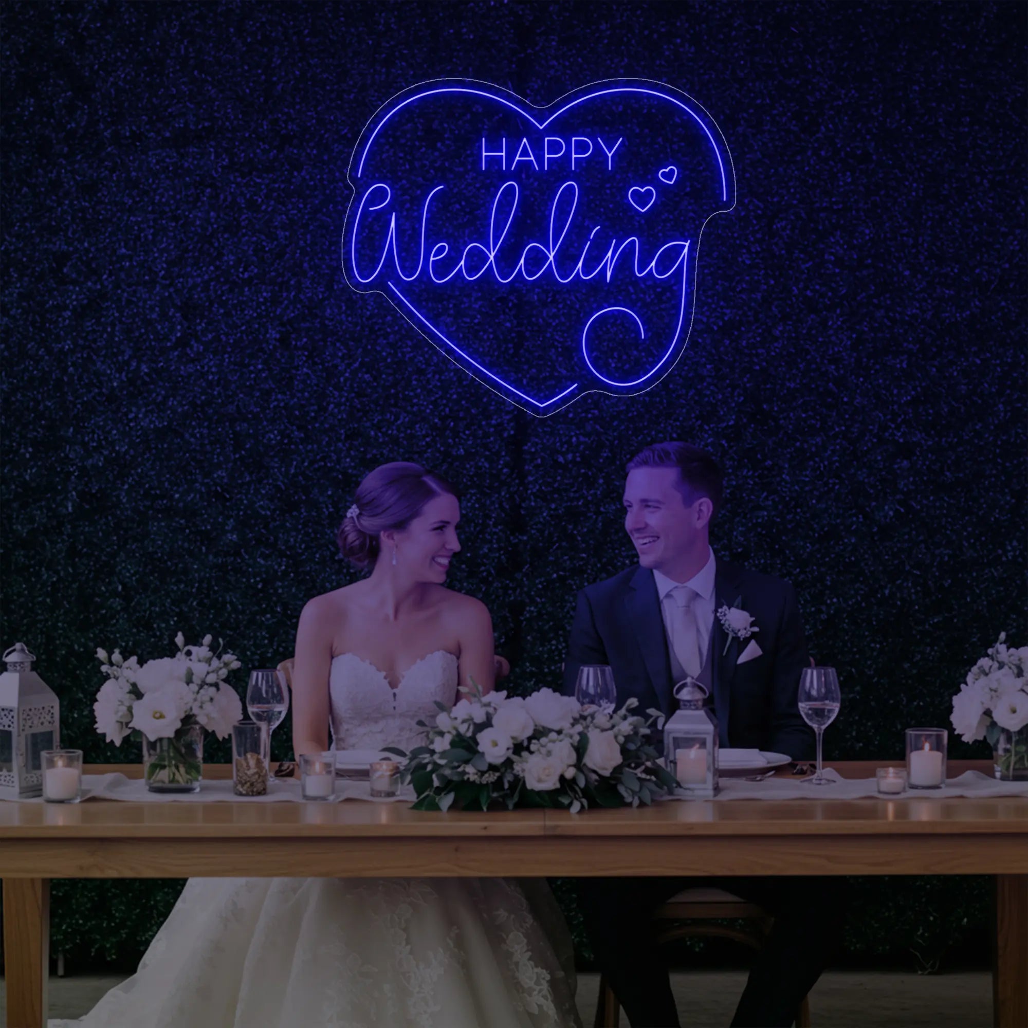 Photo of the 'Happy Wedding' neon sign glowing in deep blue against a styled interior wall.