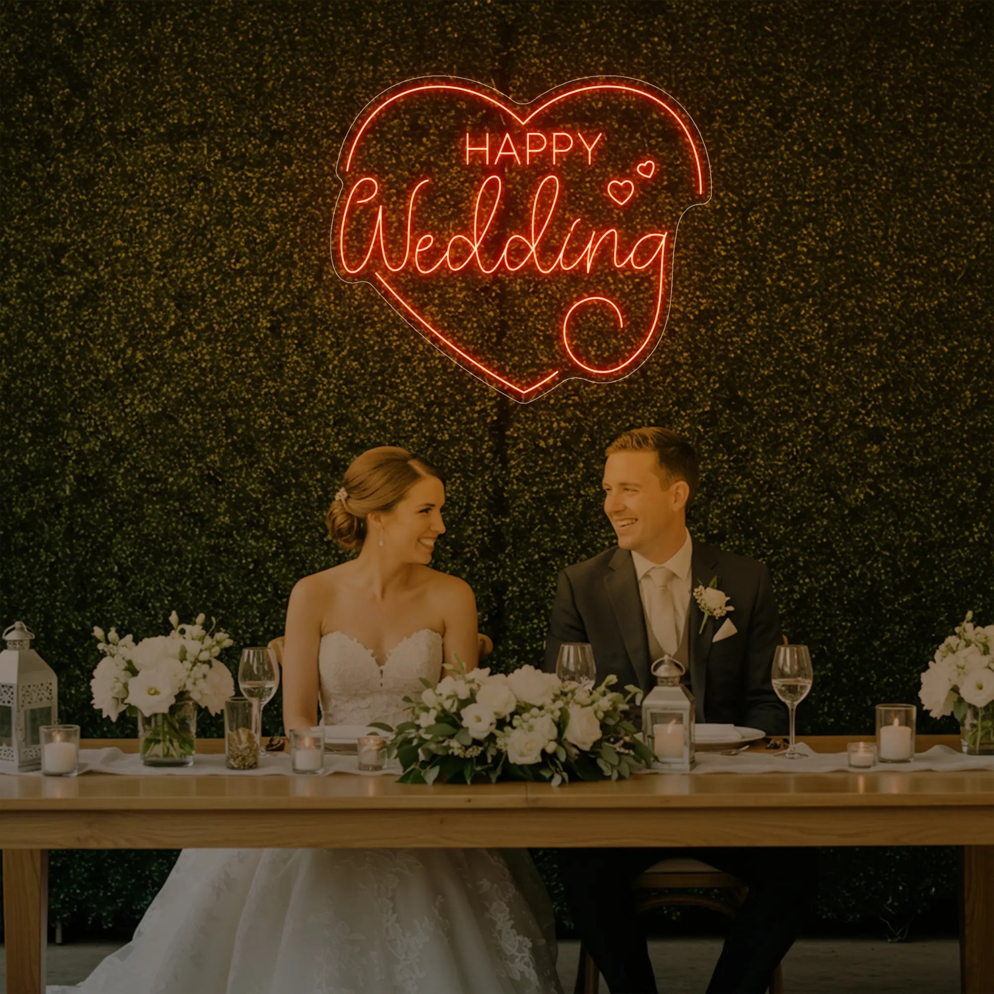 Photo of the 'Happy Wedding' neon sign glowing in golden yellow against a styled interior wall.