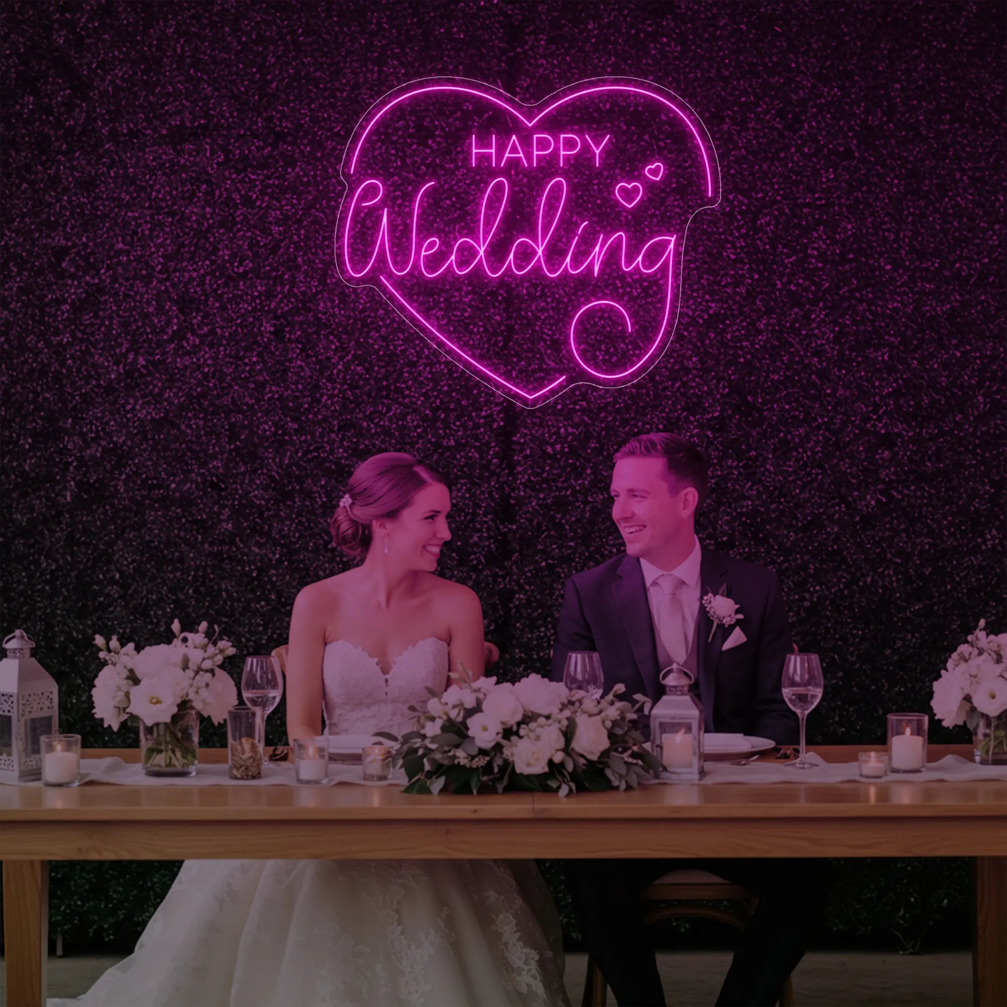 Photo of the 'Happy Wedding' neon sign glowing in light pink against a styled interior wall.