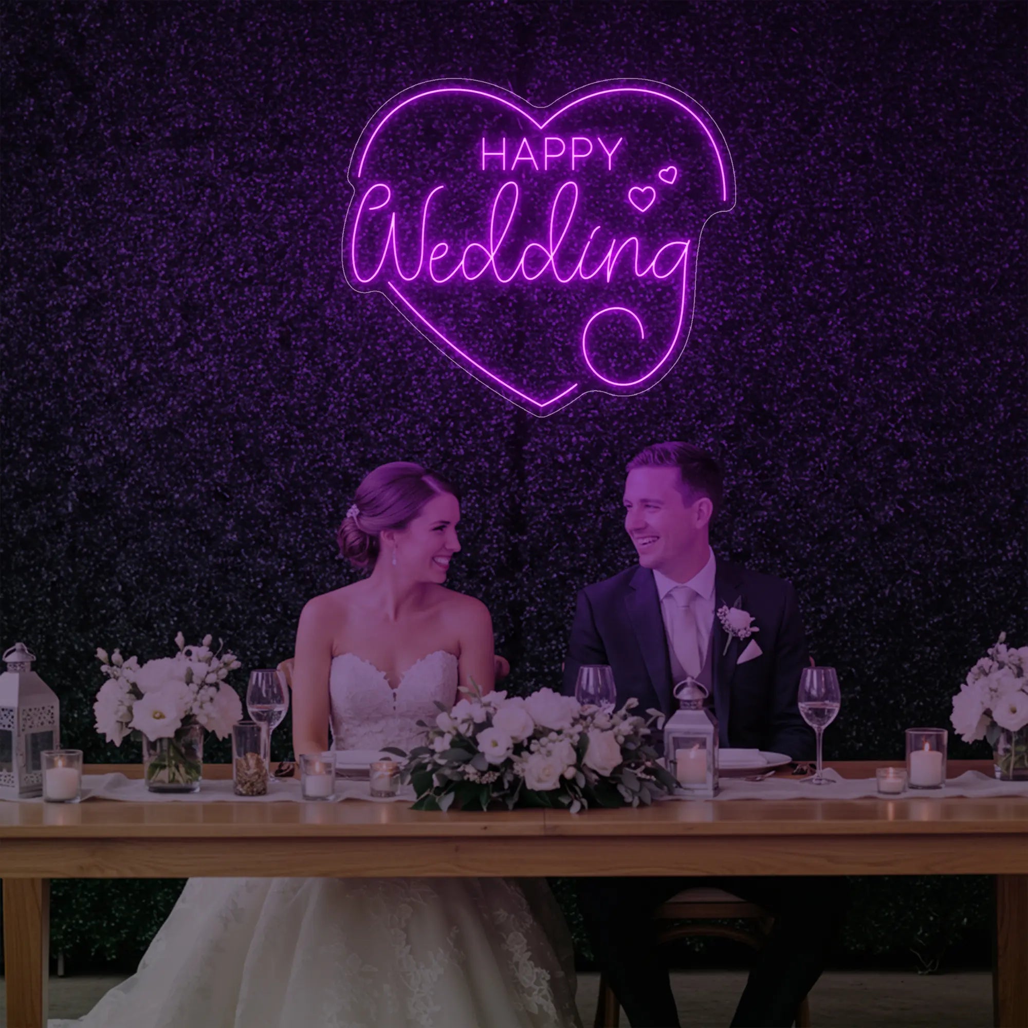 Photo of the 'Happy Wedding' neon sign glowing in deep pink against a styled interior wall.