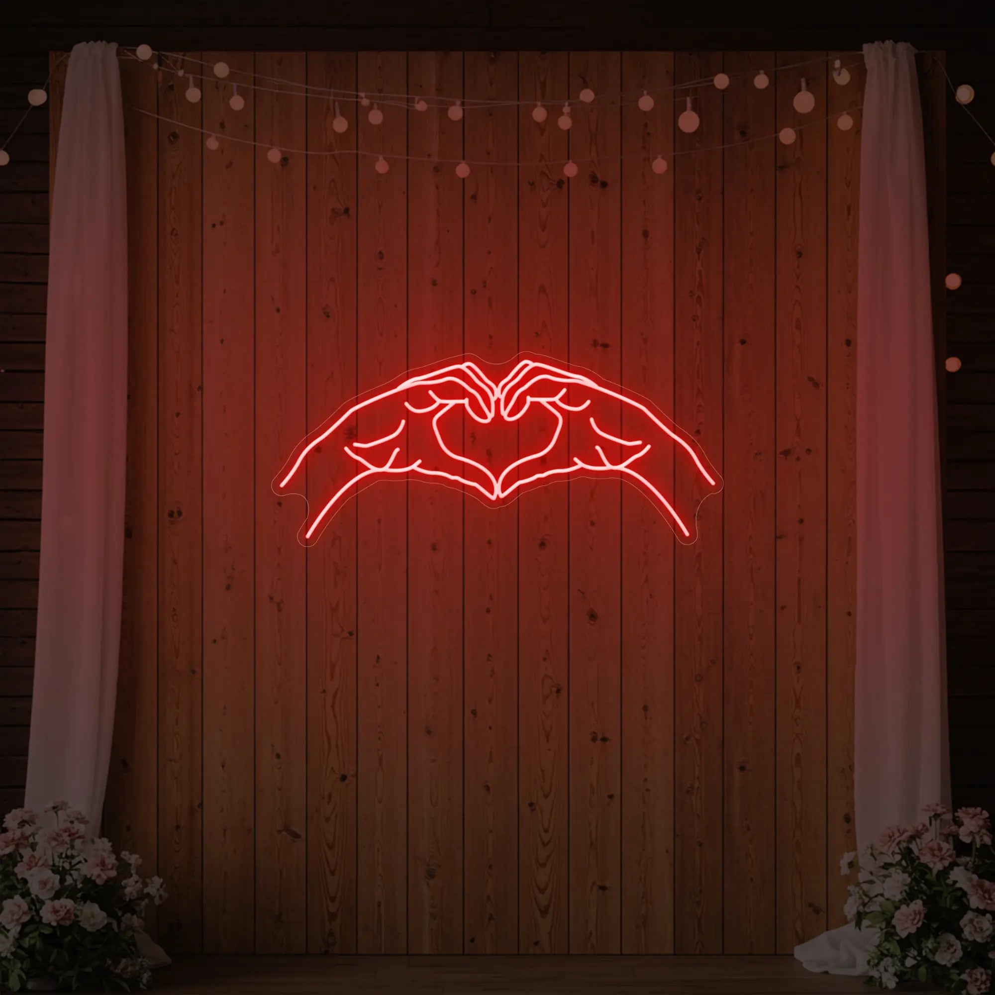 Photo of the 'Heart Hands' neon sign glowing in red against a styled interior wall.