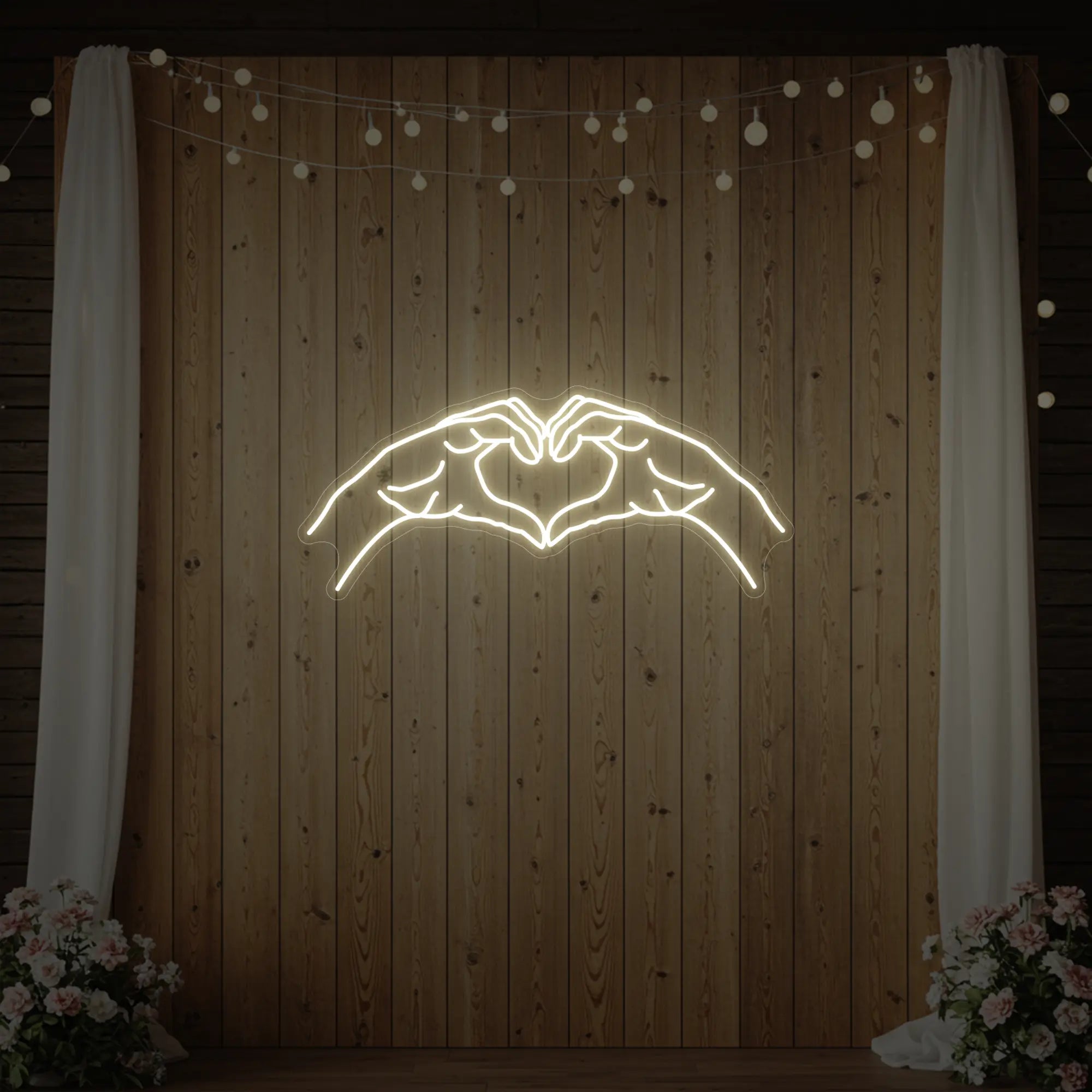 Photo of the 'Heart Hands' neon sign glowing in warm white against a styled interior wall.