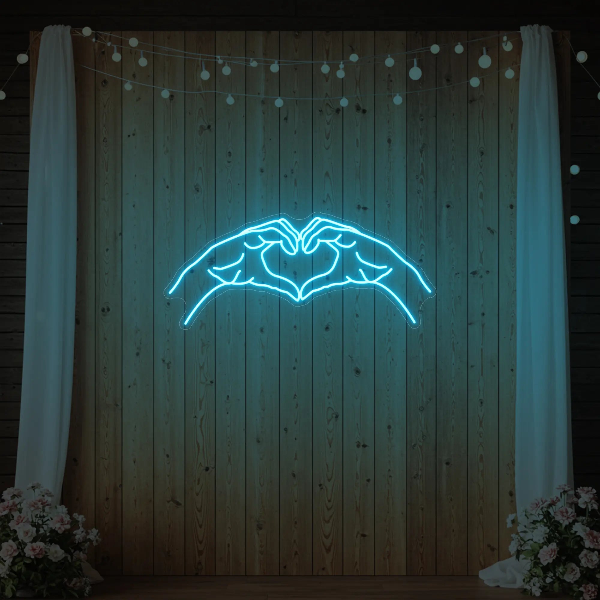 Photo of the 'Heart Hands' neon sign glowing in ice blue against a styled interior wall.