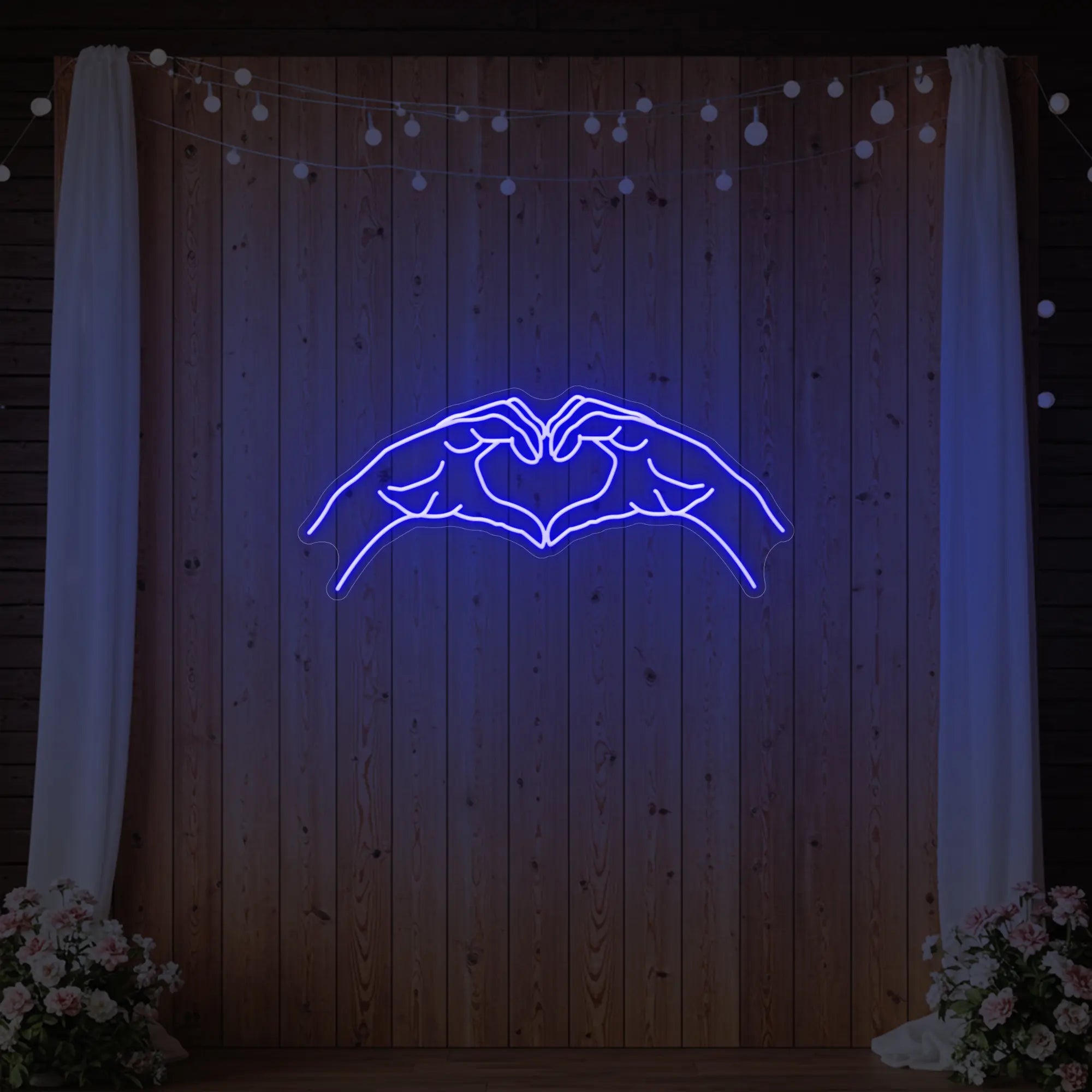 Photo of the 'Heart Hands' neon sign glowing in deep blue against a styled interior wall.