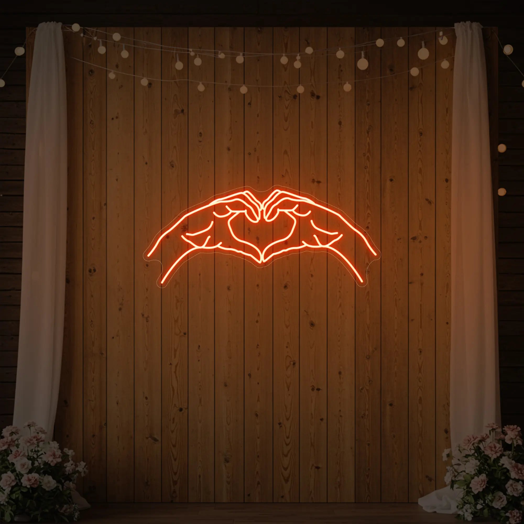 Photo of the 'Heart Hands' neon sign glowing in golden yellow against a styled interior wall.