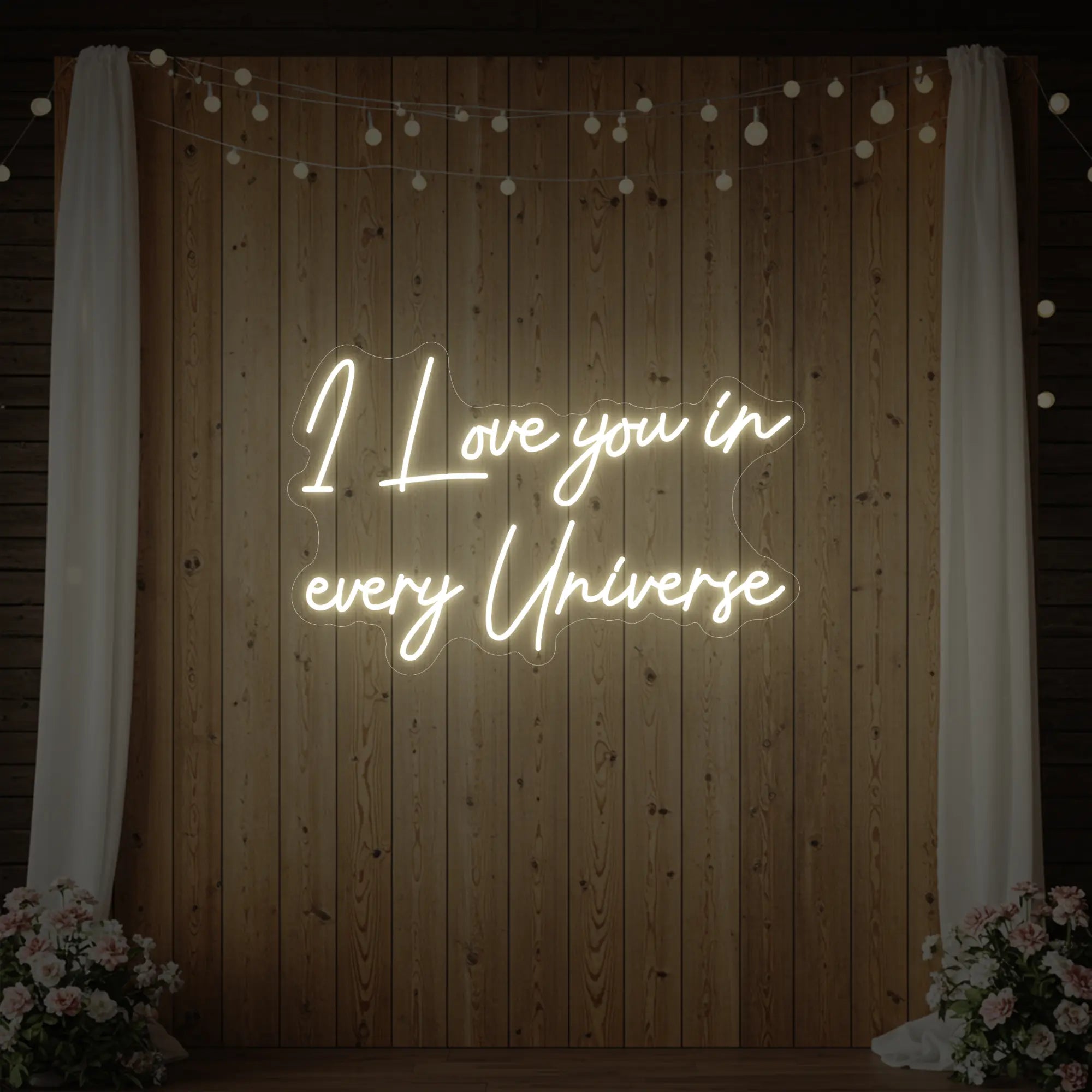 Photo of the 'I Love You In Every Universe' neon sign glowing in warm white against a styled interior wall.