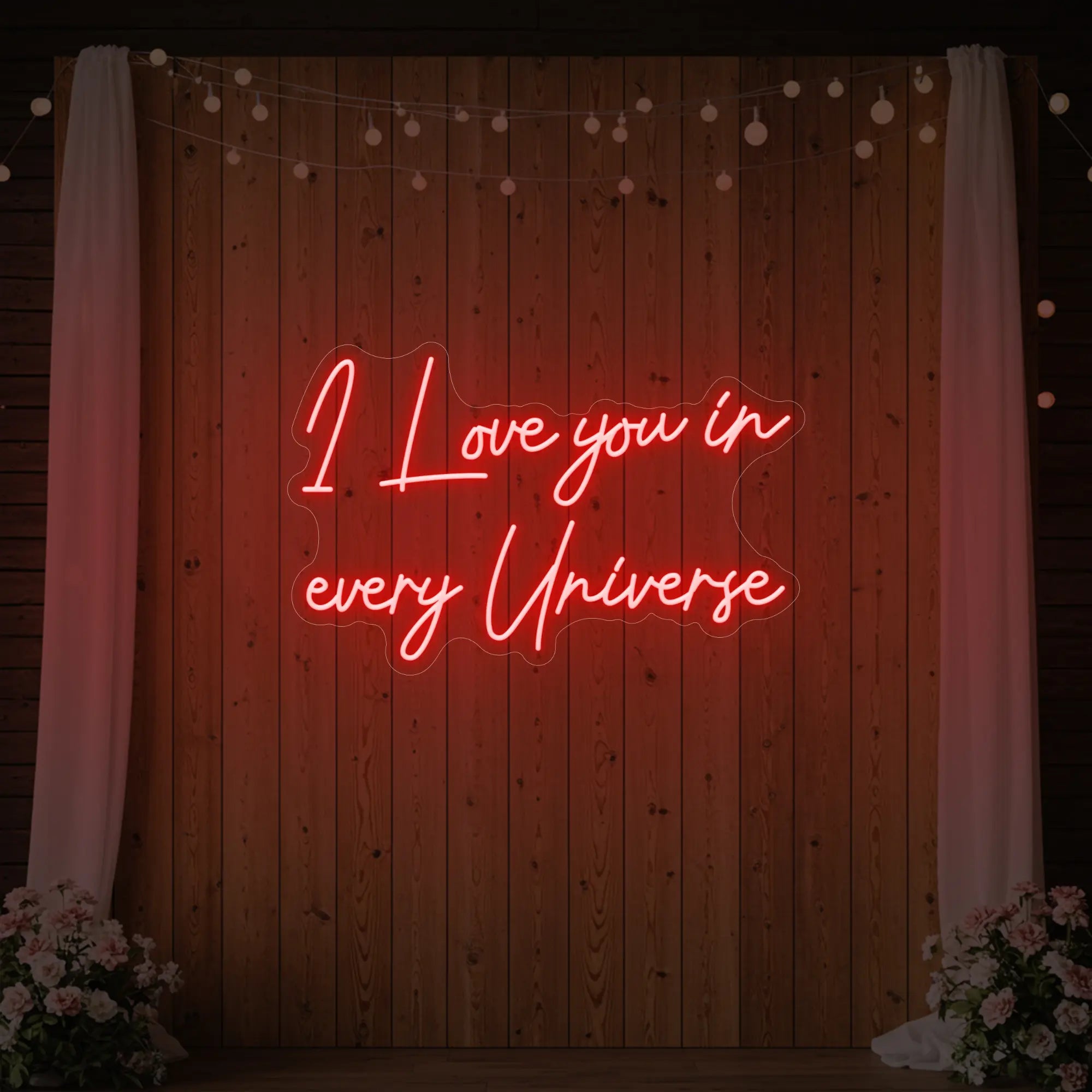 Photo of the 'I Love You In Every Universe' neon sign glowing in red against a styled interior wall.