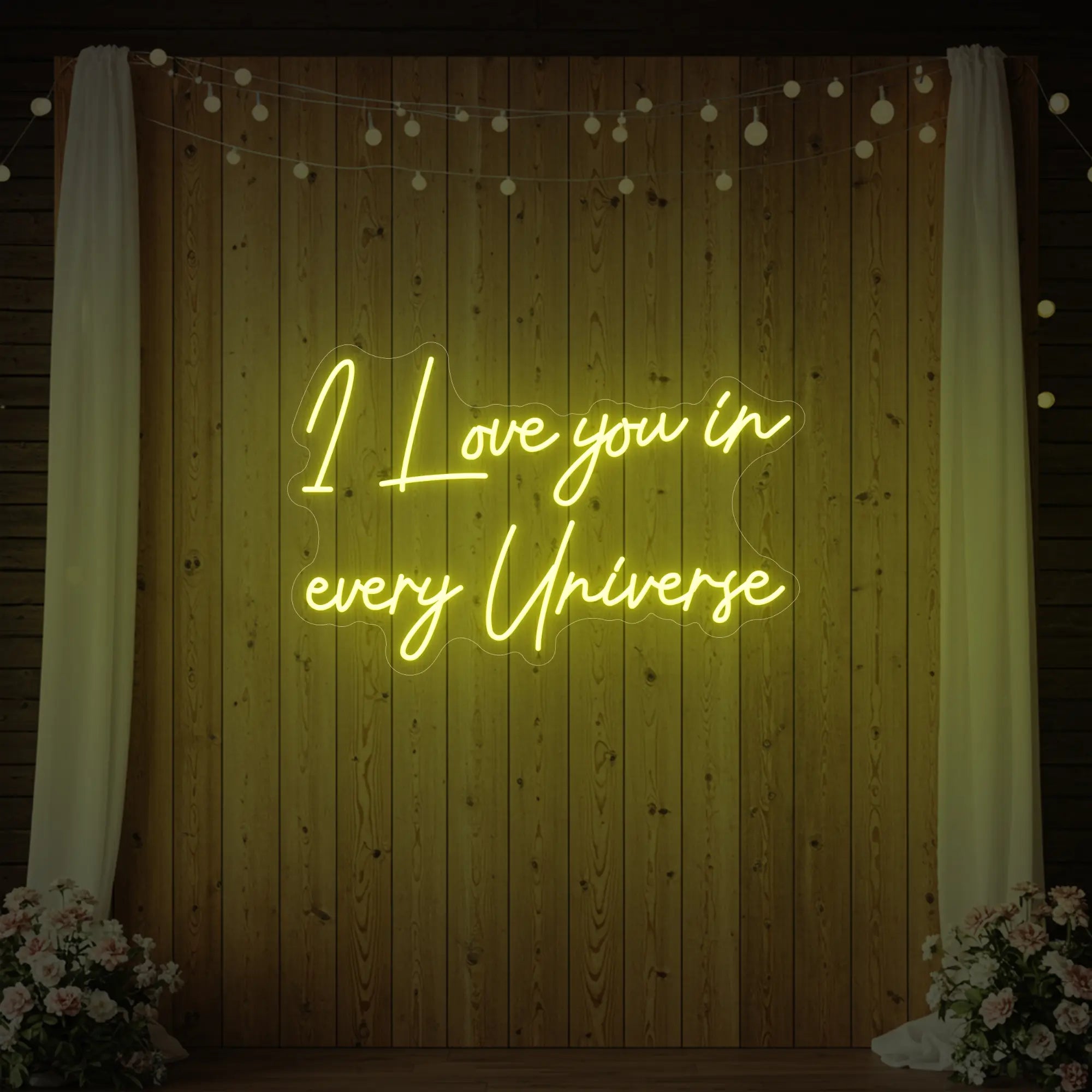 Photo of the 'I Love You In Every Universe' neon sign glowing in lemon yellow against a styled interior wall.
