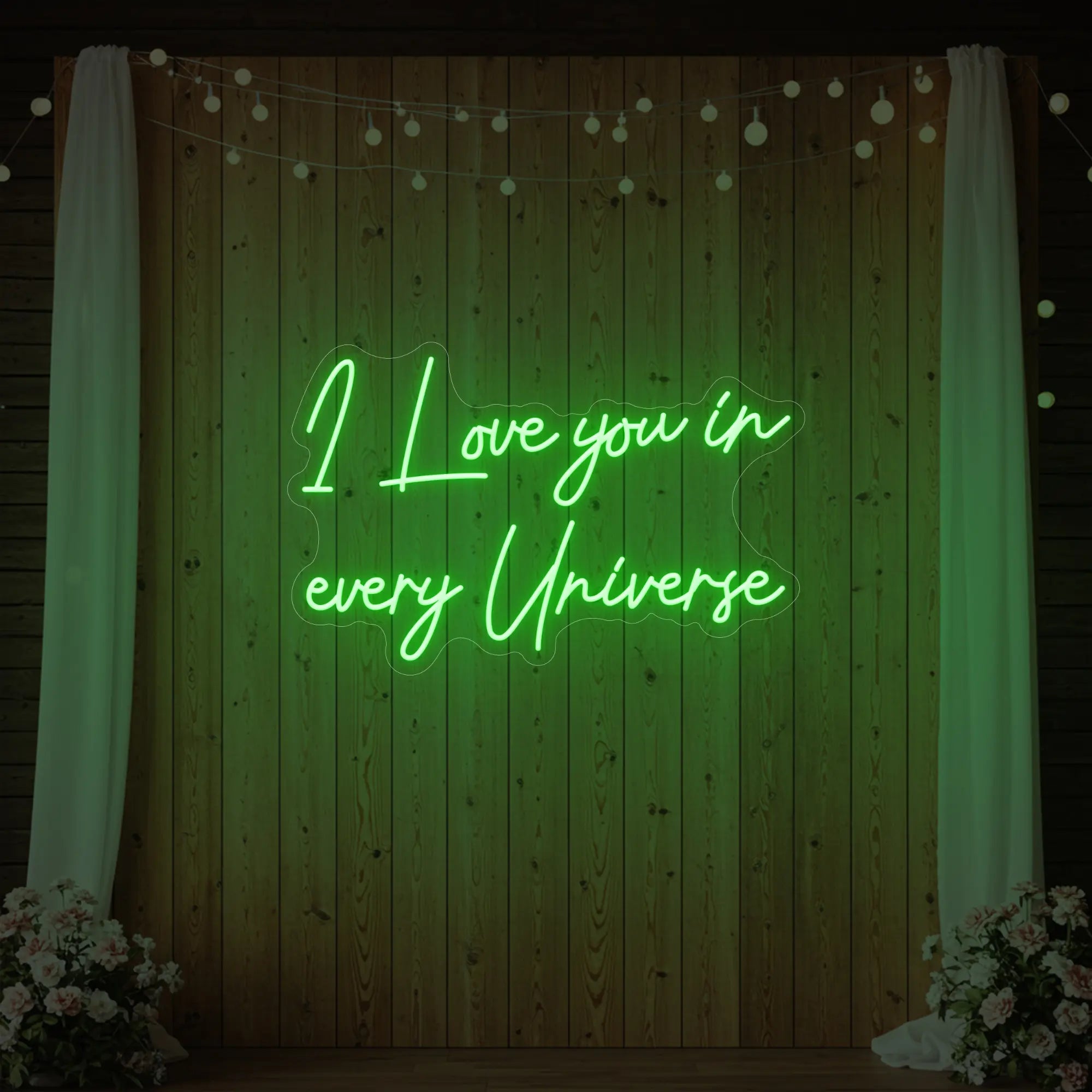 Photo of the 'I Love You In Every Universe' neon sign glowing in green against a styled interior wall.