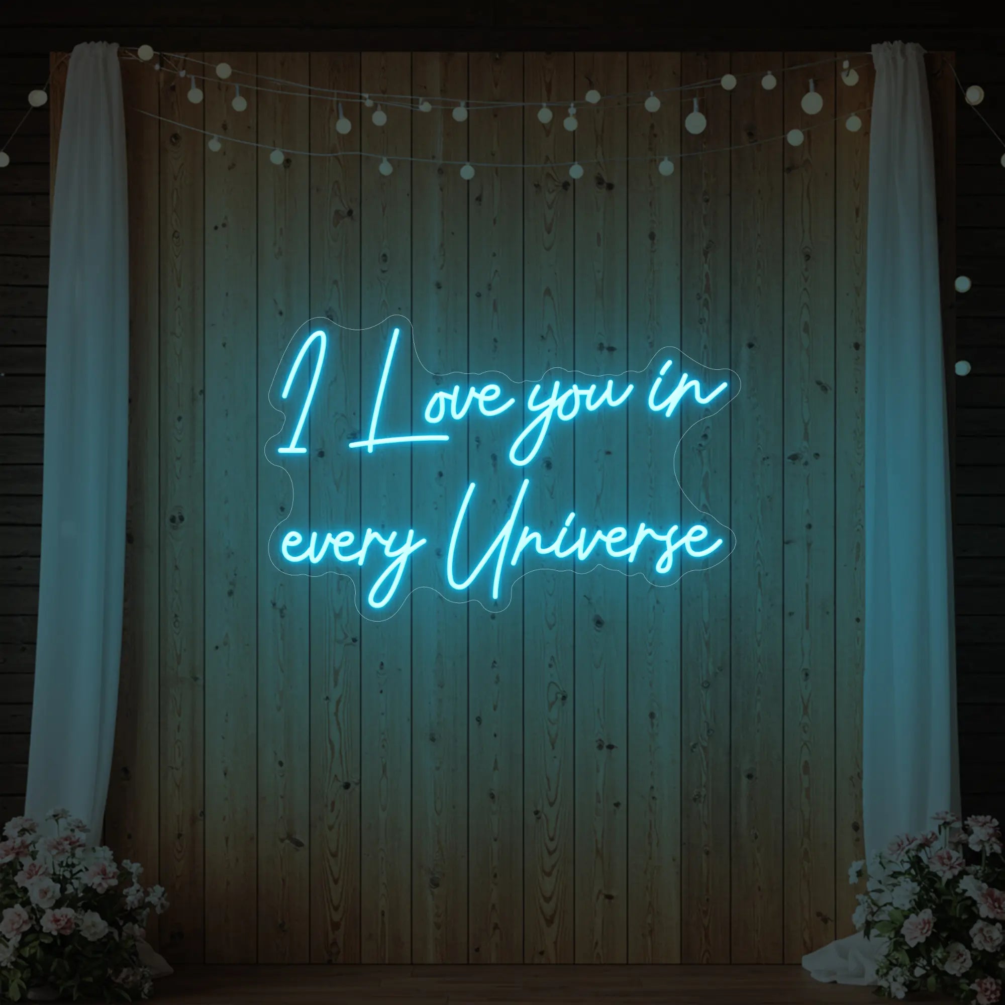 Photo of the 'I Love You In Every Universe' neon sign glowing in ice blue against a styled interior wall.