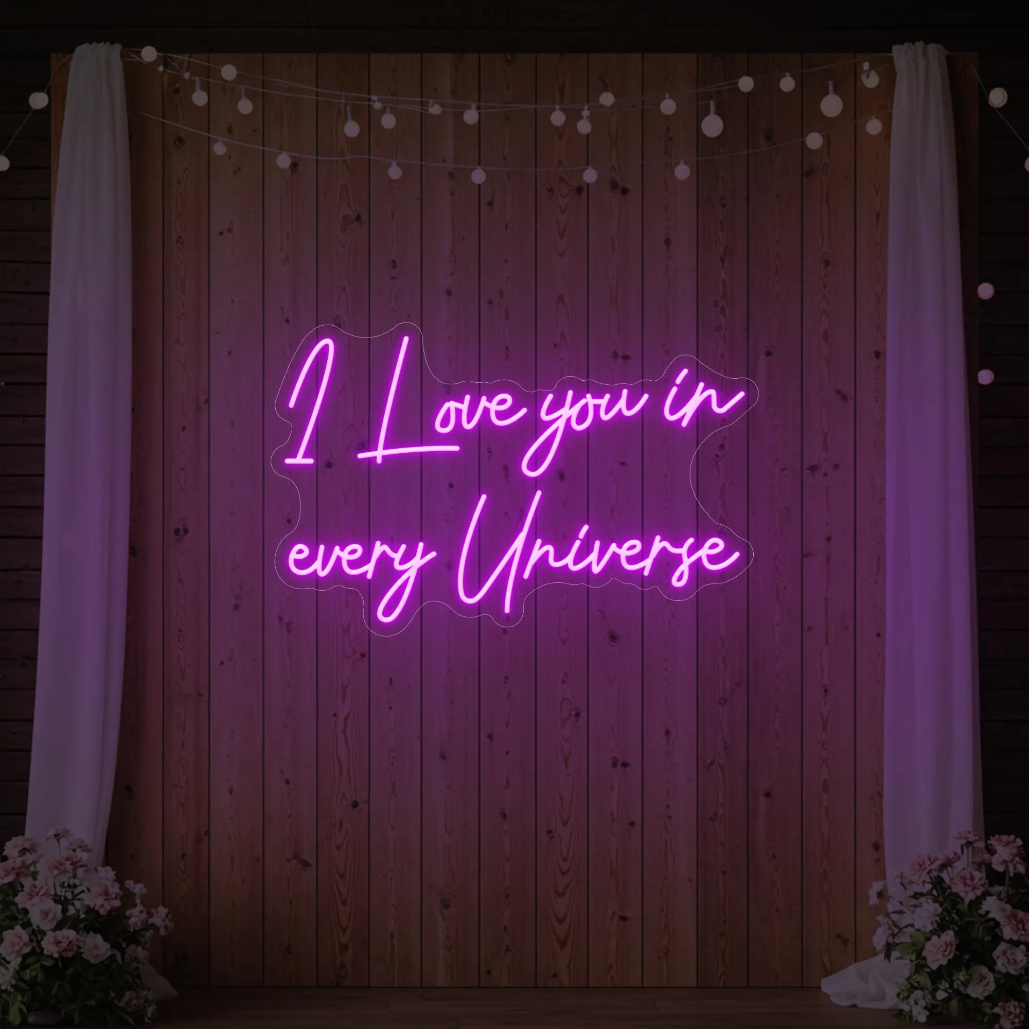 Photo of the 'I Love You In Every Universe' neon sign glowing in deep pink against a styled interior wall.