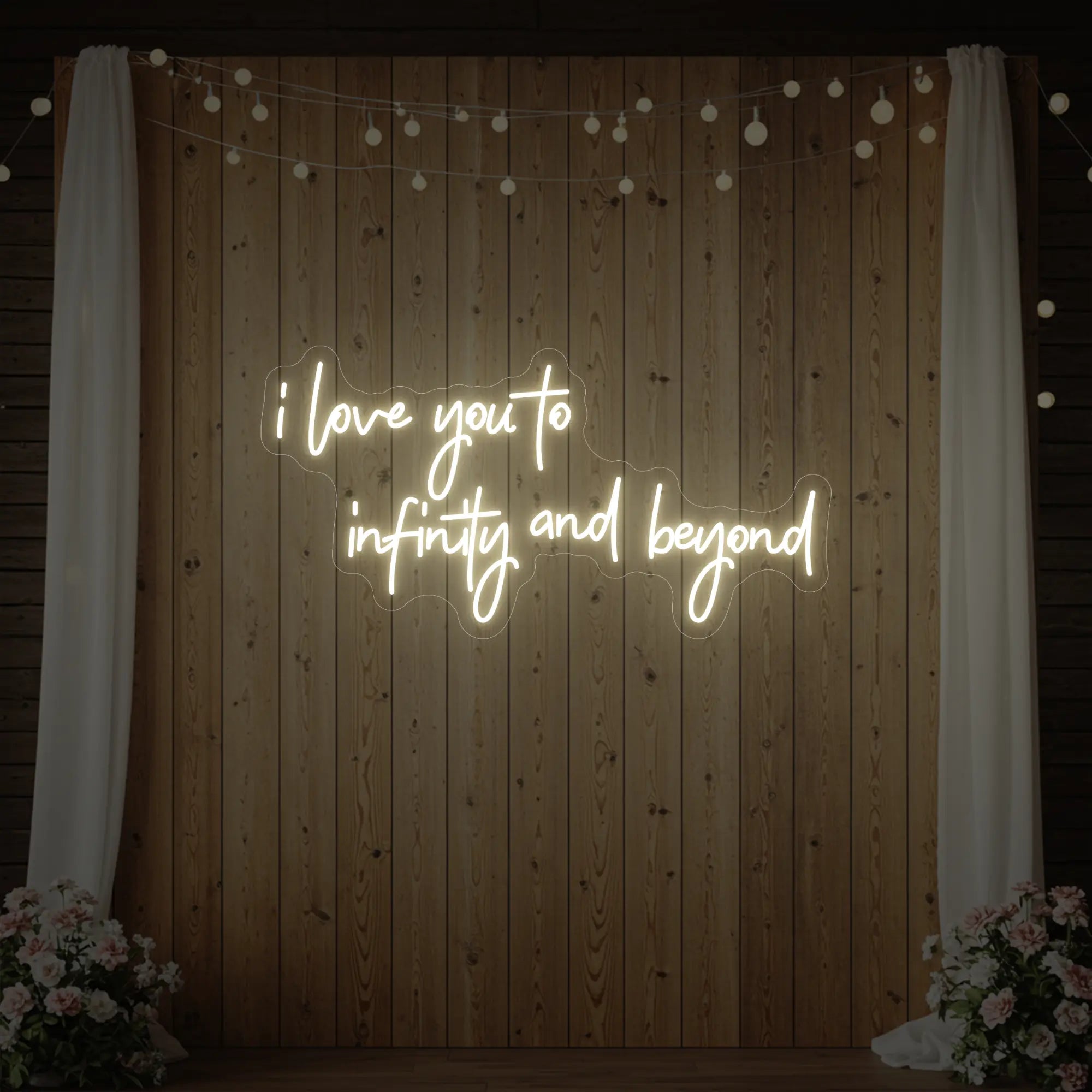 Photo of the 'I Love You to Infinity and Beyond' neon sign glowing in warm white against a styled interior wall.