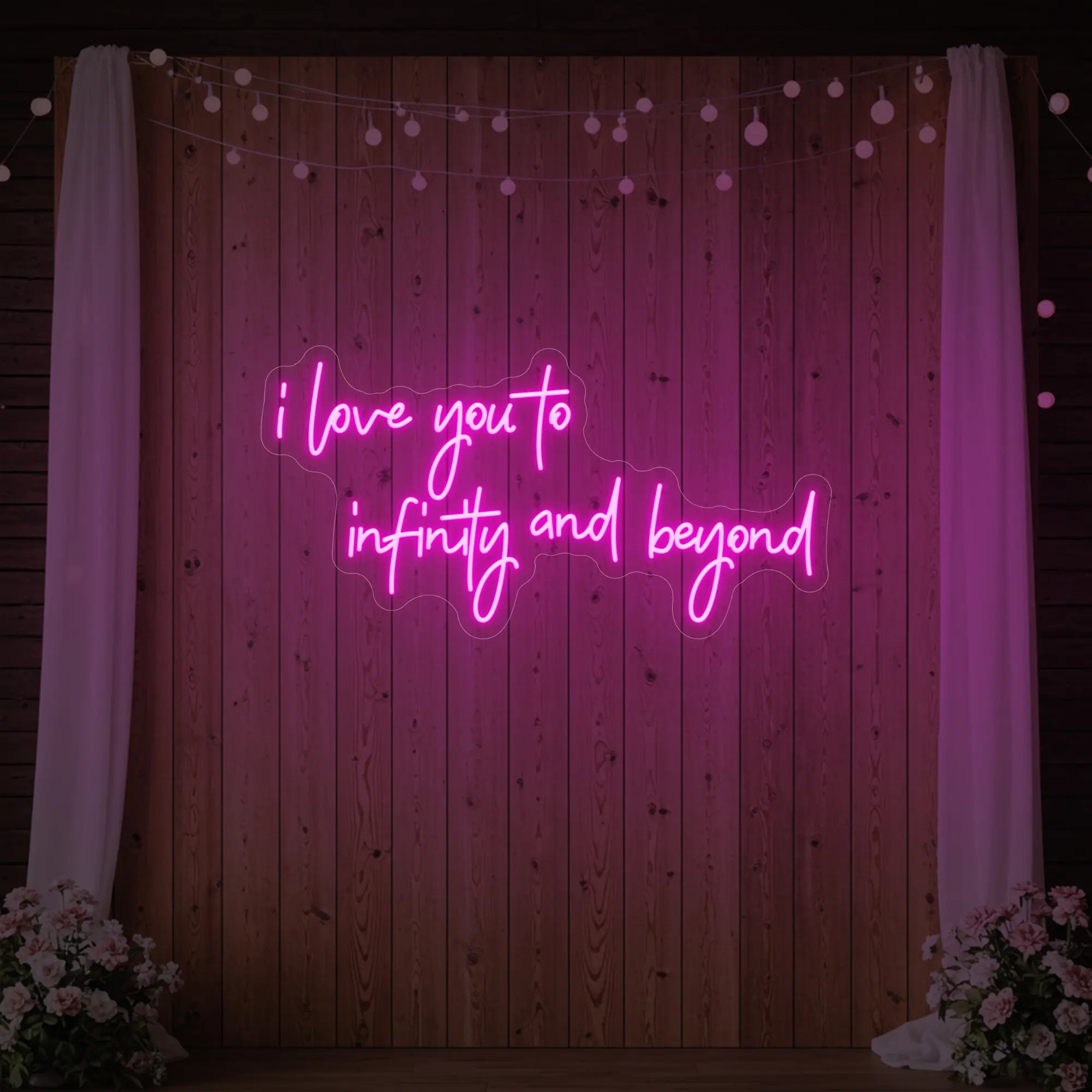 Photo of the 'I Love You to Infinity and Beyond' neon sign glowing in light pink against a styled interior wall.