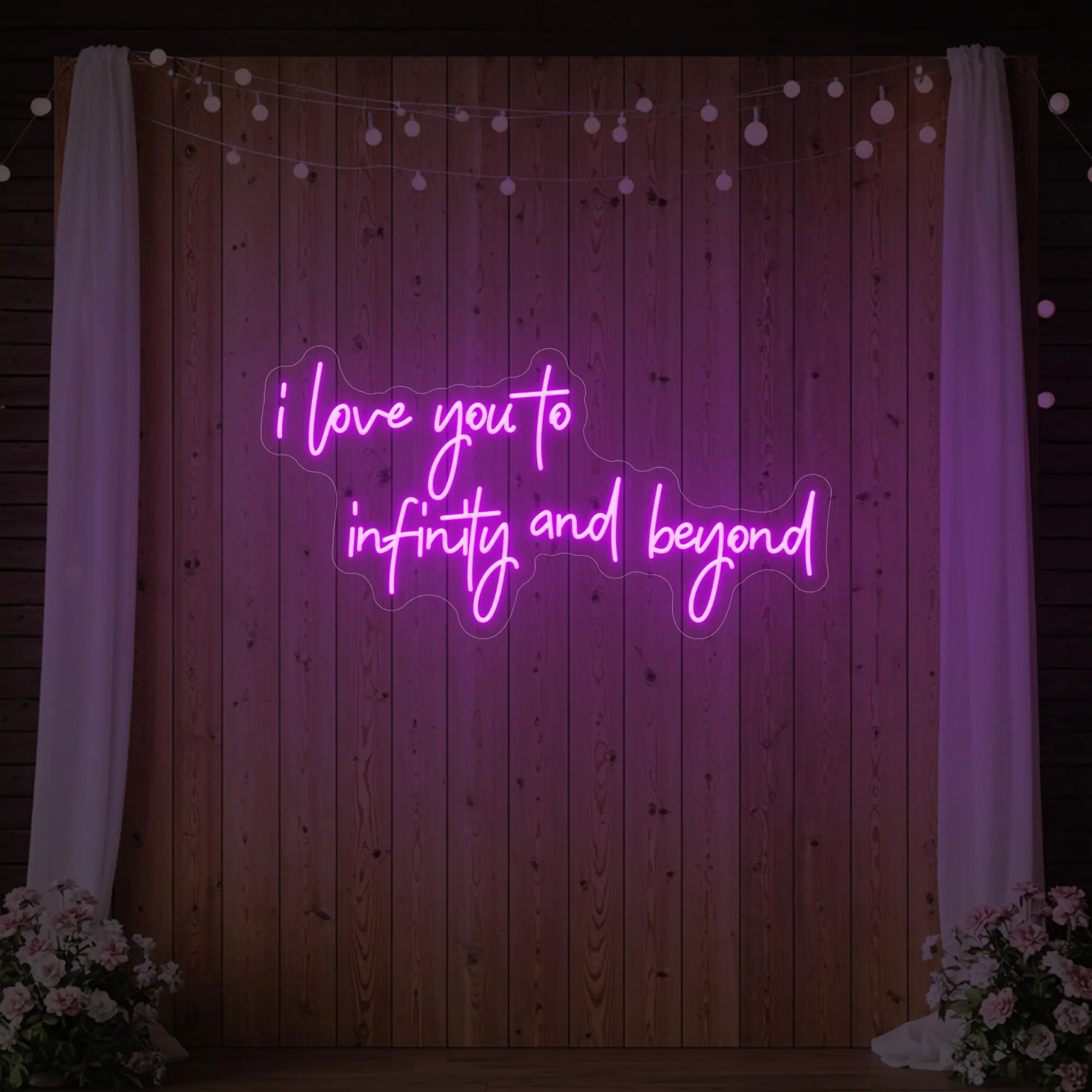 Photo of the 'I Love You to Infinity and Beyond' neon sign glowing in deep pink against a styled interior wall.