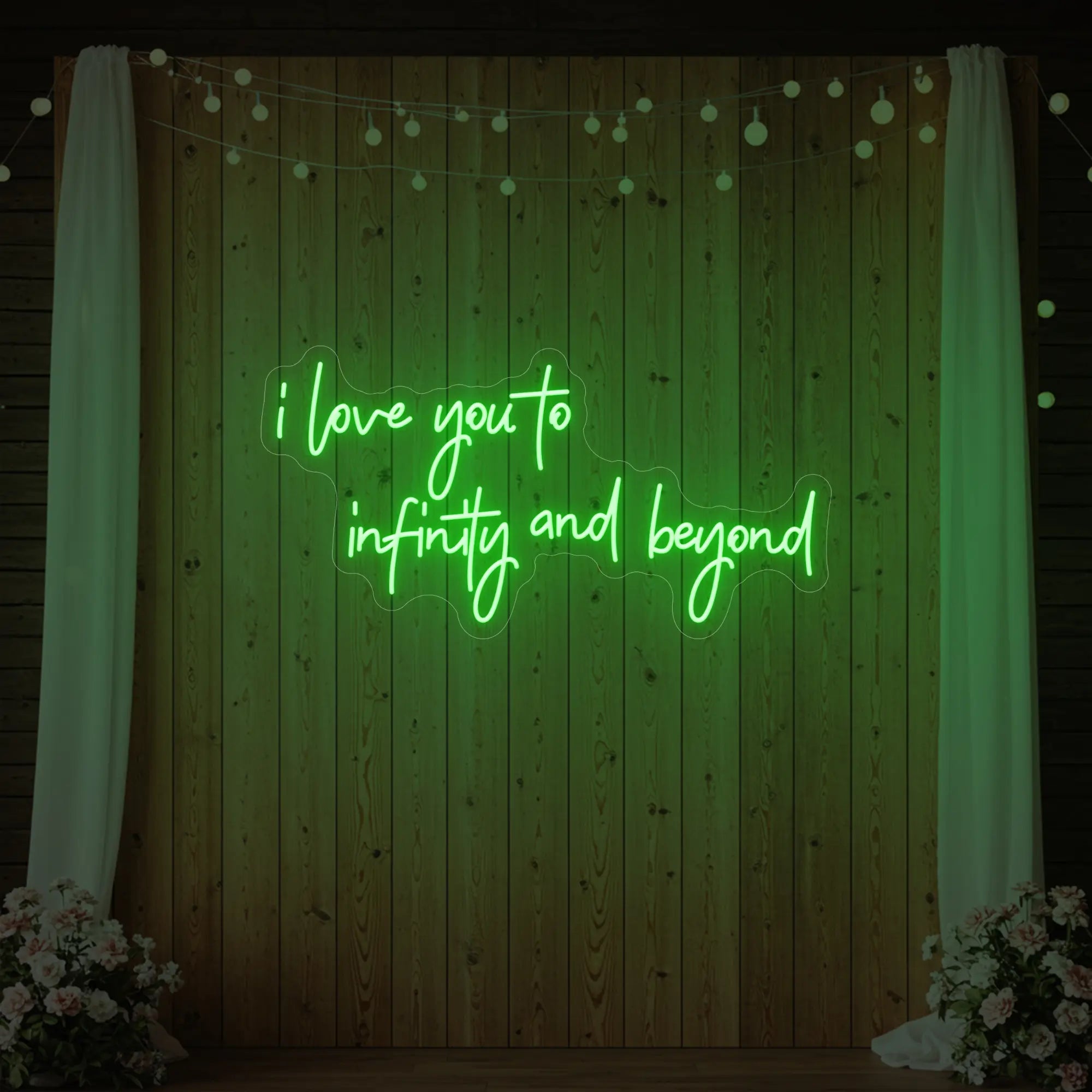 Photo of the 'I Love You to Infinity and Beyond' neon sign glowing in green against a styled interior wall.