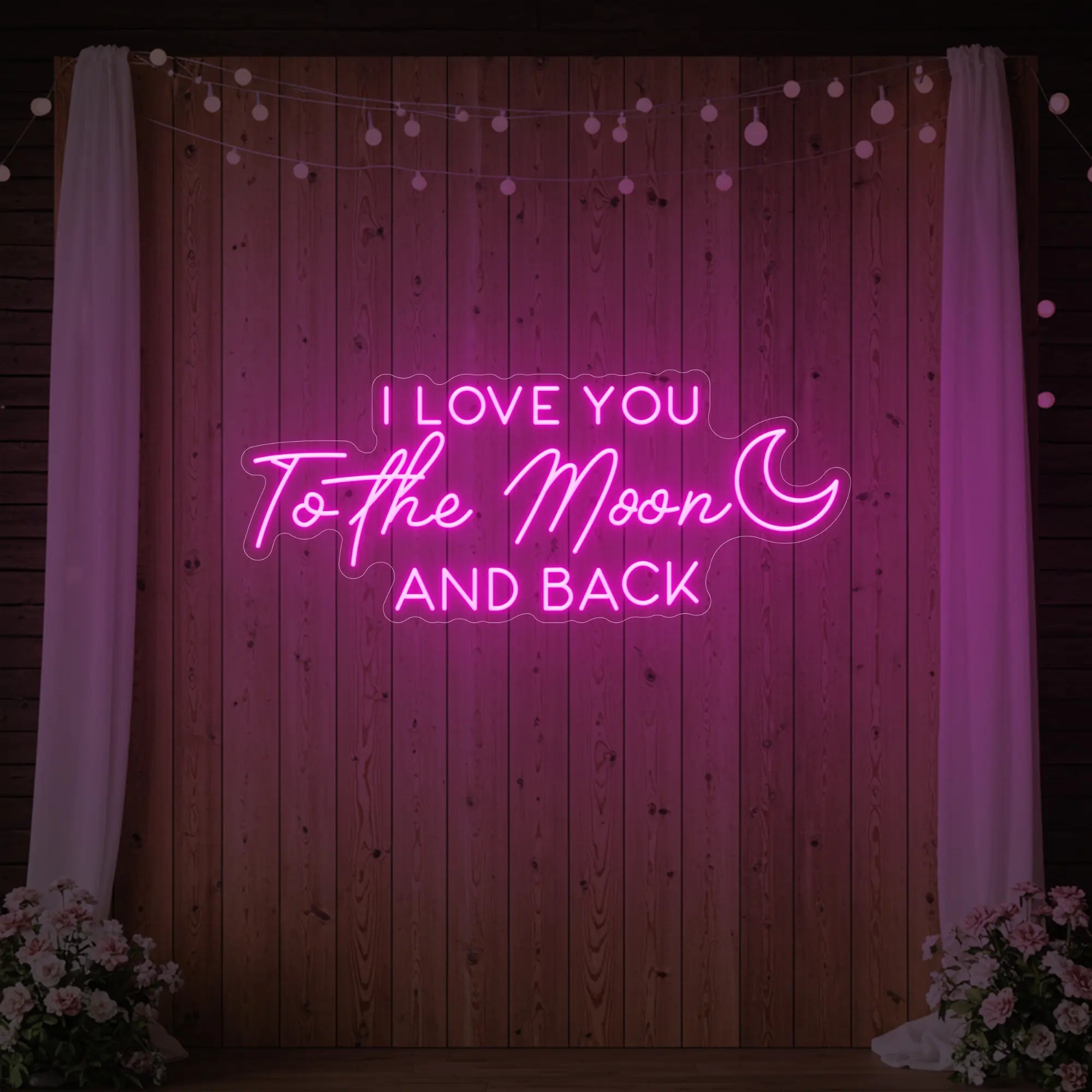 Photo of the 'I Love You To The Moon And Back' neon sign glowing in light pink against a styled interior wall.