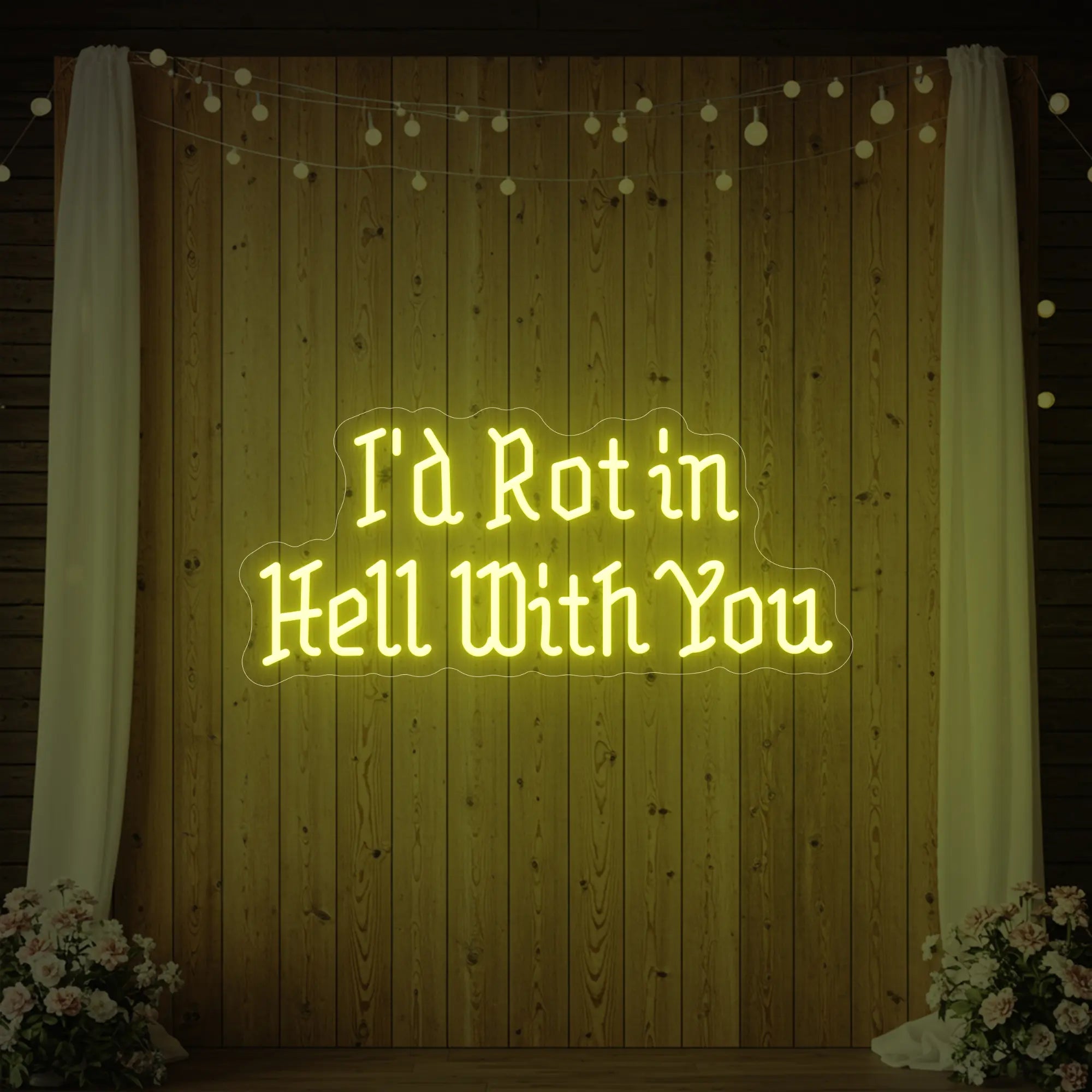 Photo of the 'I’d Rot in Hell With You' neon sign glowing in lemon yellow against a styled interior wall.