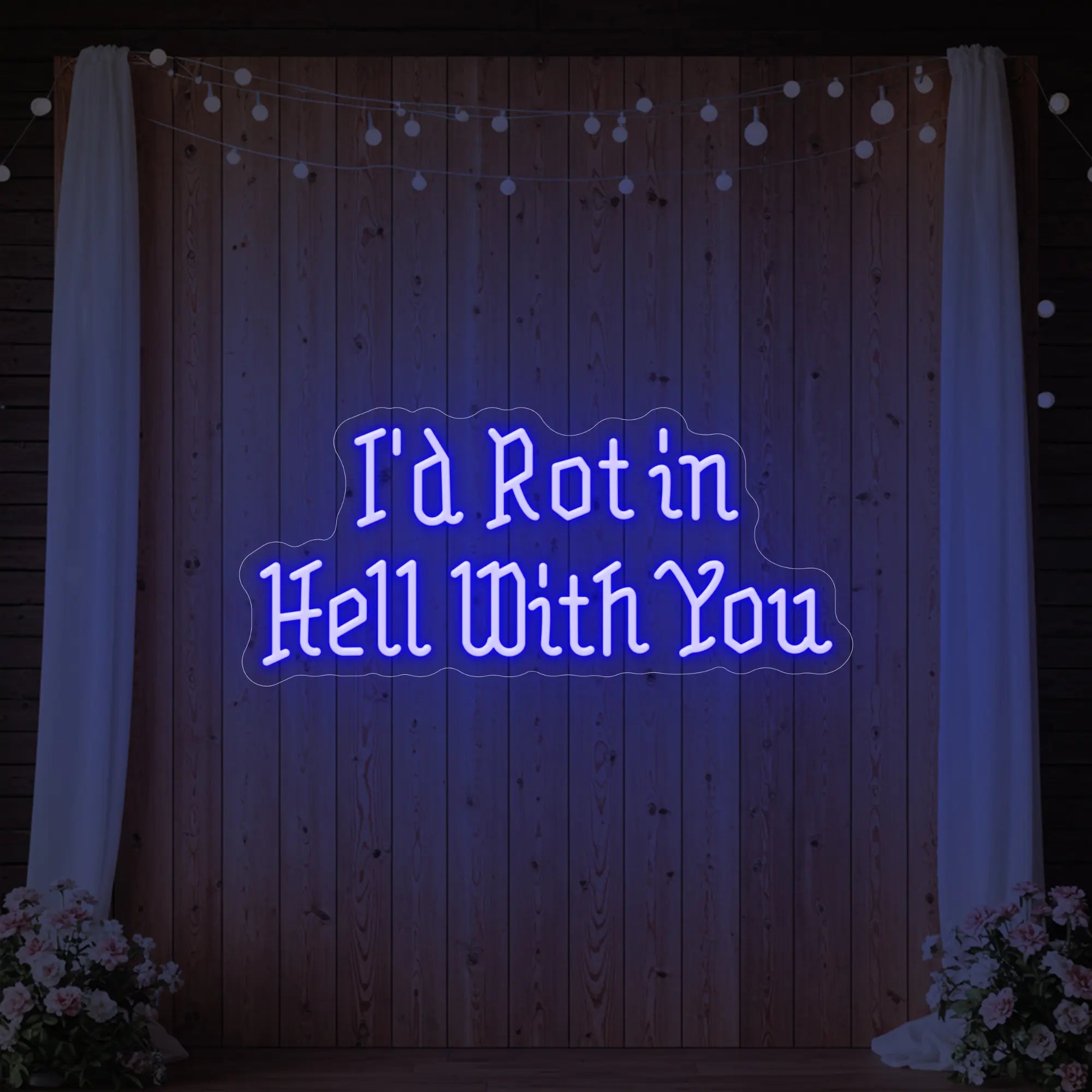 Photo of the 'I’d Rot in Hell With You' neon sign glowing in deep blue against a styled interior wall.