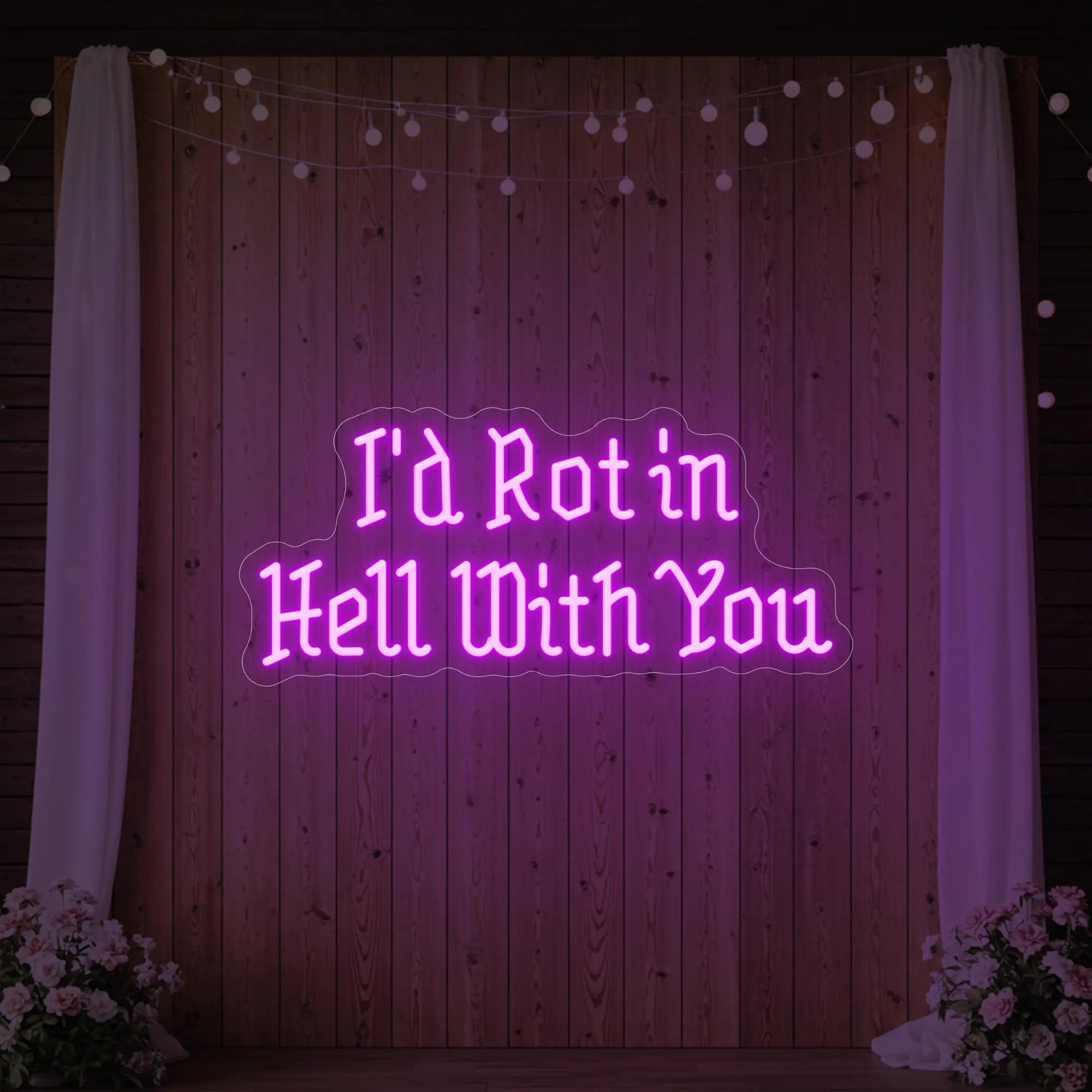 Photo of the 'I’d Rot in Hell With You' neon sign glowing in deep pink against a styled interior wall.