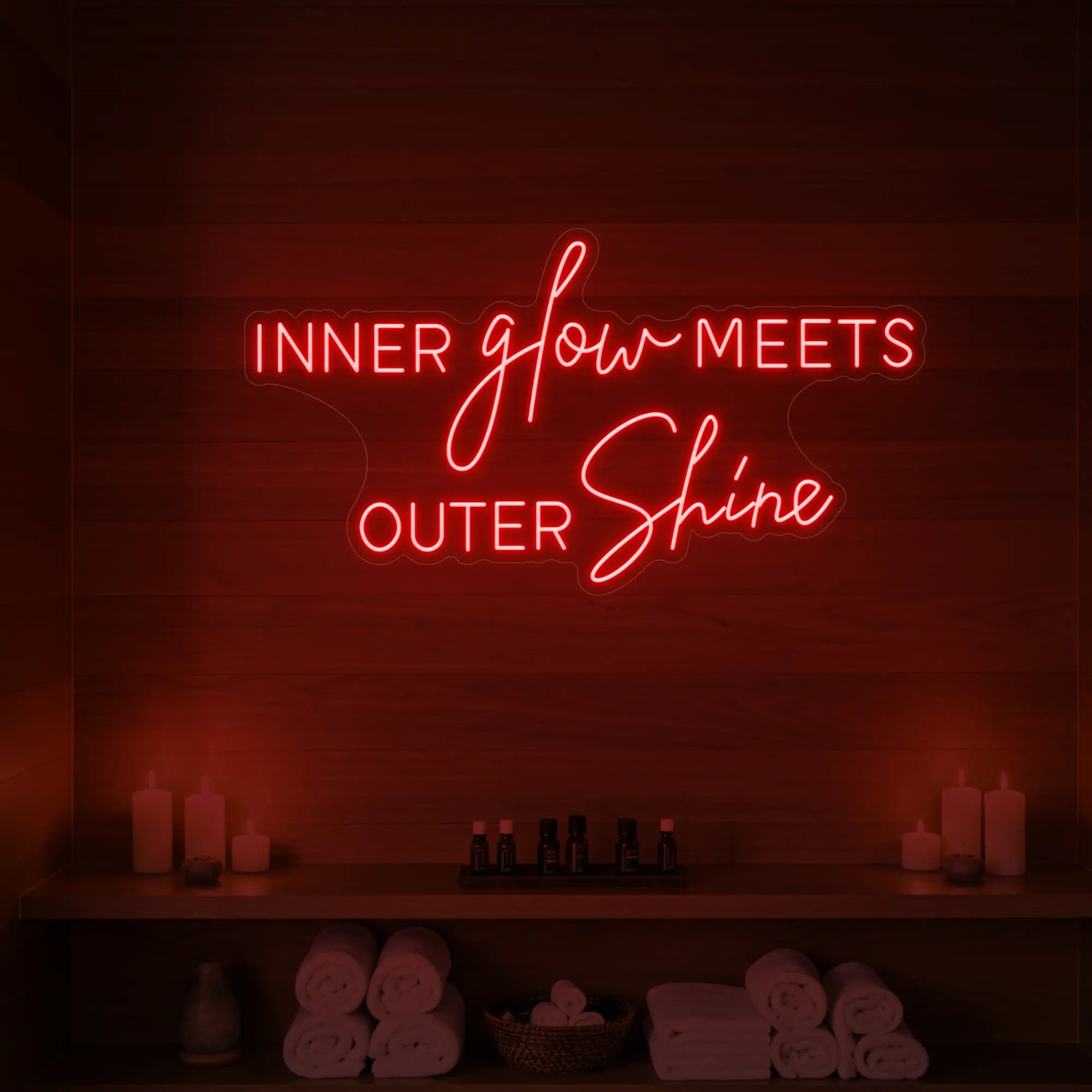 Photo of the 'INNER glow MEETS OUTER Shine' neon sign glowing in red against a styled interior wall.