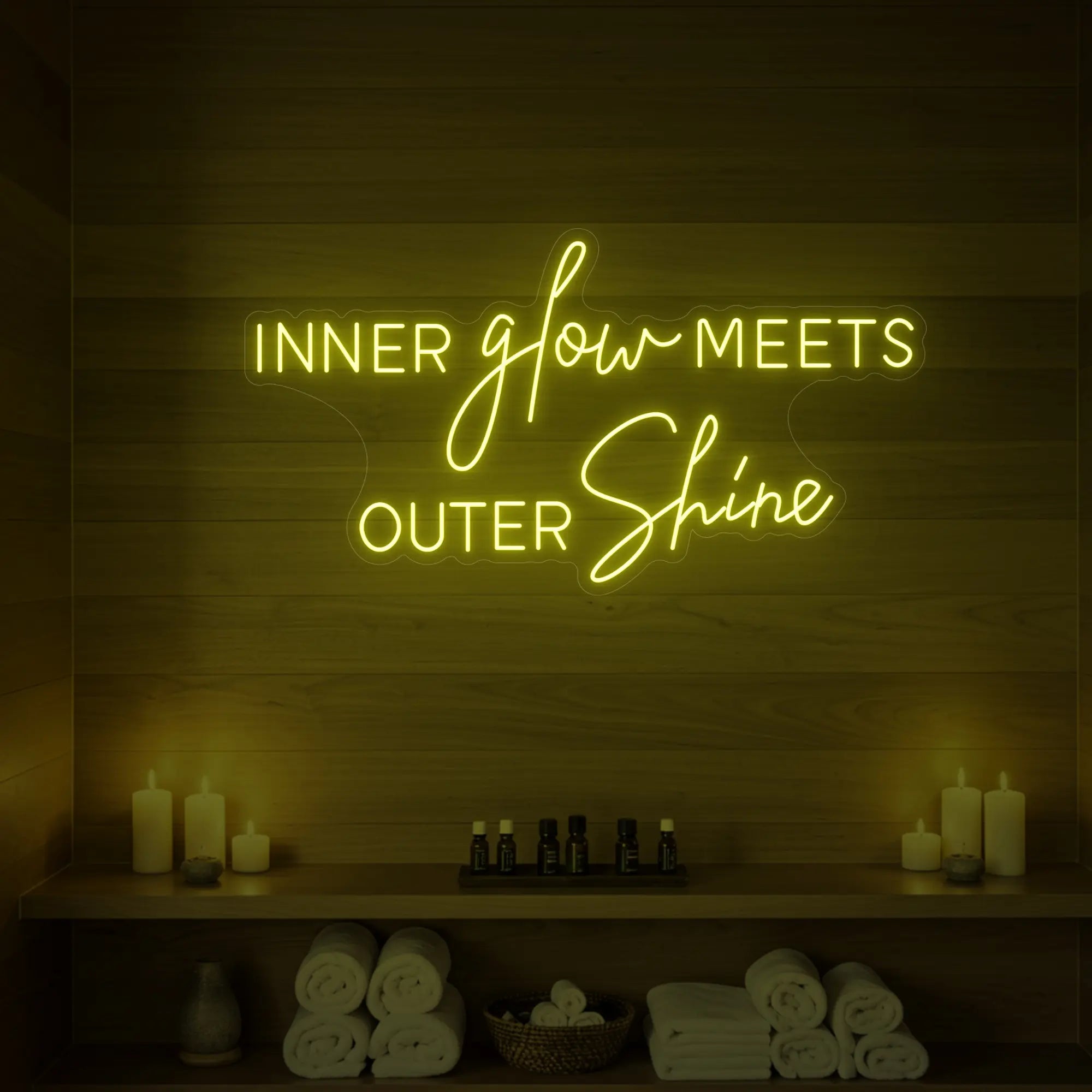 Photo of the 'INNER glow MEETS OUTER Shine' neon sign glowing in lemon yellow against a styled interior wall.
