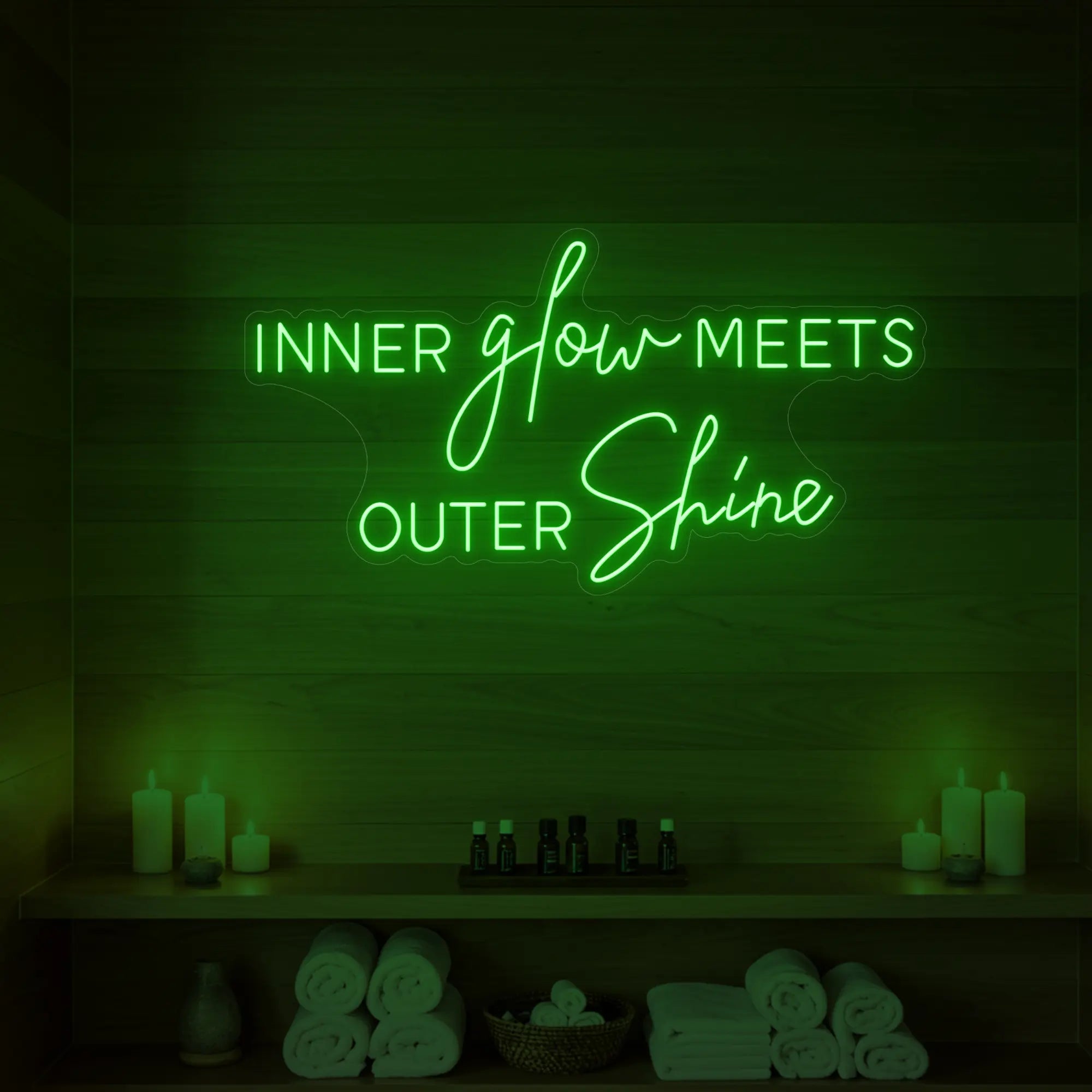 Photo of the 'INNER glow MEETS OUTER Shine' neon sign glowing in green against a styled interior wall.