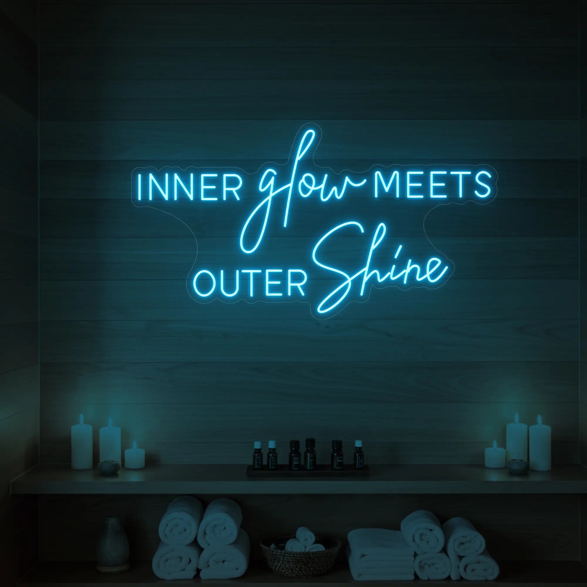 Photo of the 'INNER glow MEETS OUTER Shine' neon sign glowing in ice blue against a styled interior wall.