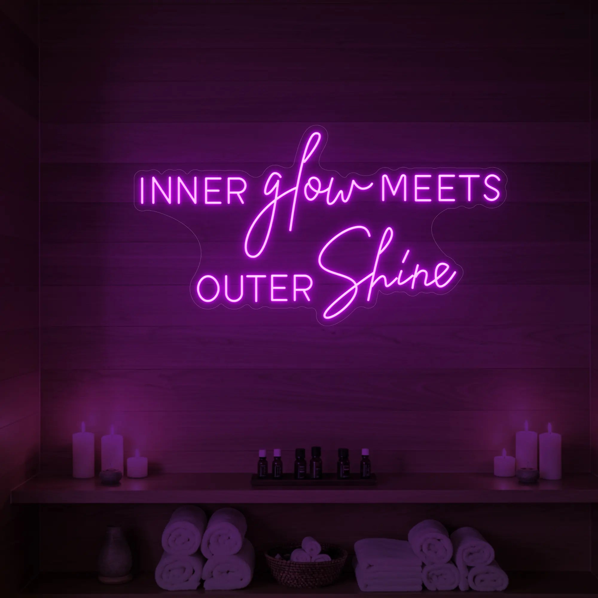 Photo of the 'INNER glow MEETS OUTER Shine' neon sign glowing in deep pink against a styled interior wall.