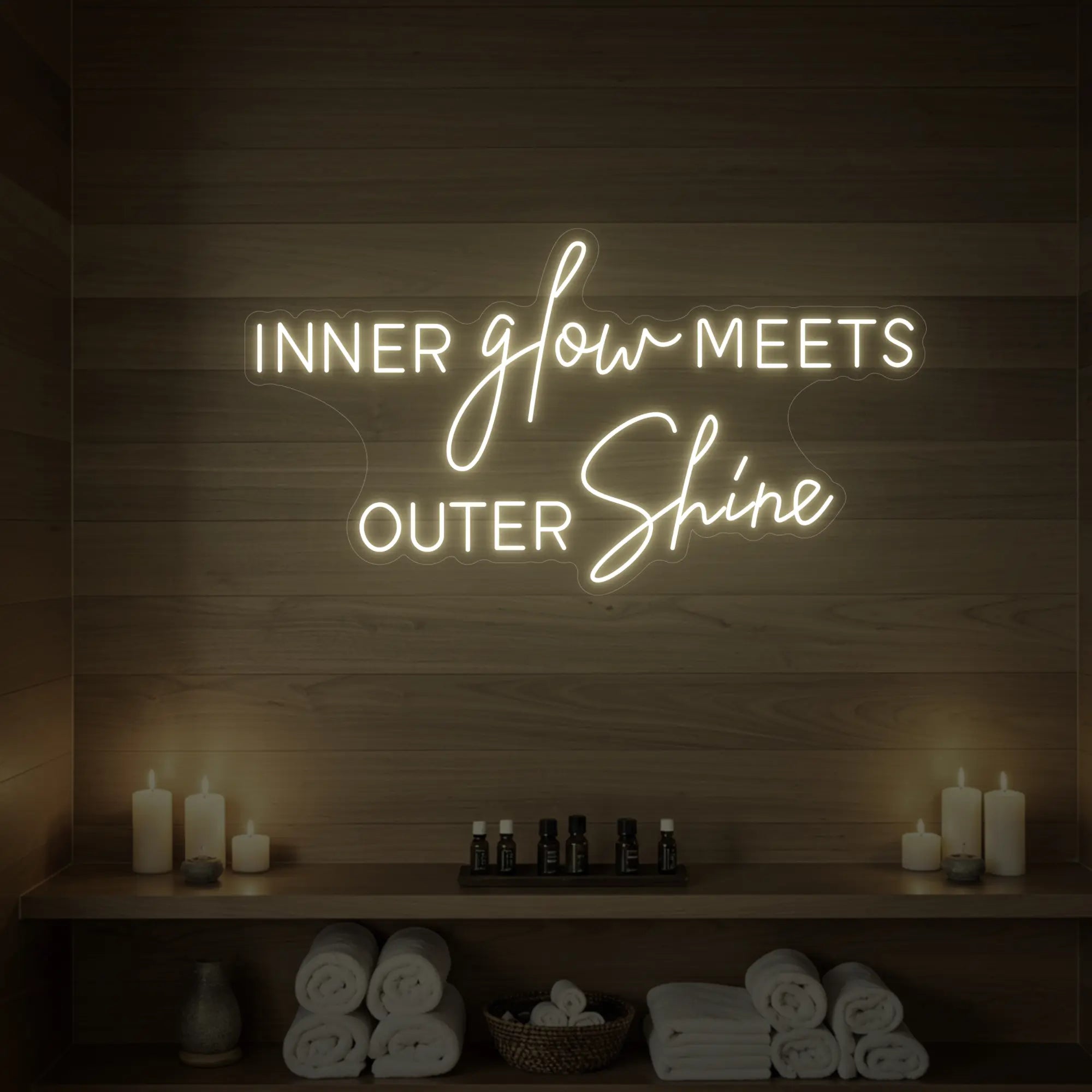 Photo of the 'INNER glow MEETS OUTER Shine' neon sign glowing in warm white against a styled interior wall.