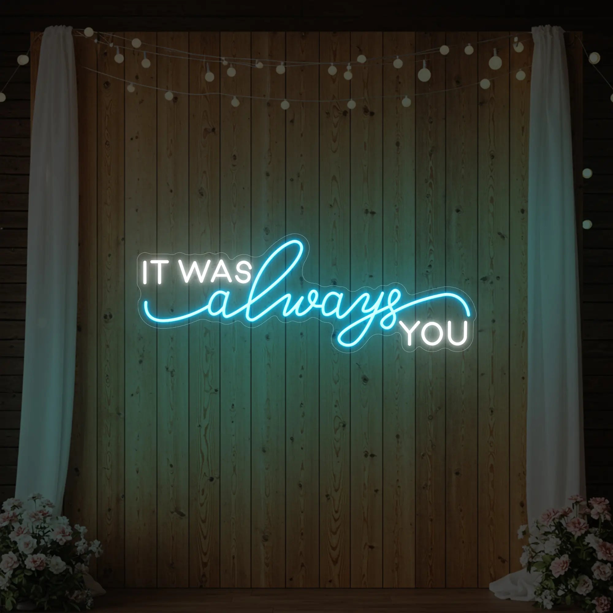 Photo of the 'It Was Always You' neon sign glowing in ice blue against a styled interior wall.