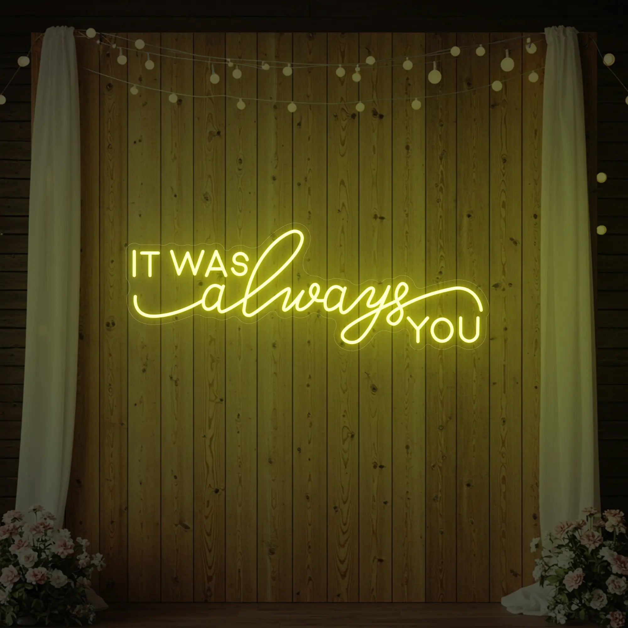 Photo of the 'It Was Always You' neon sign glowing in lemon yellow against a styled interior wall.