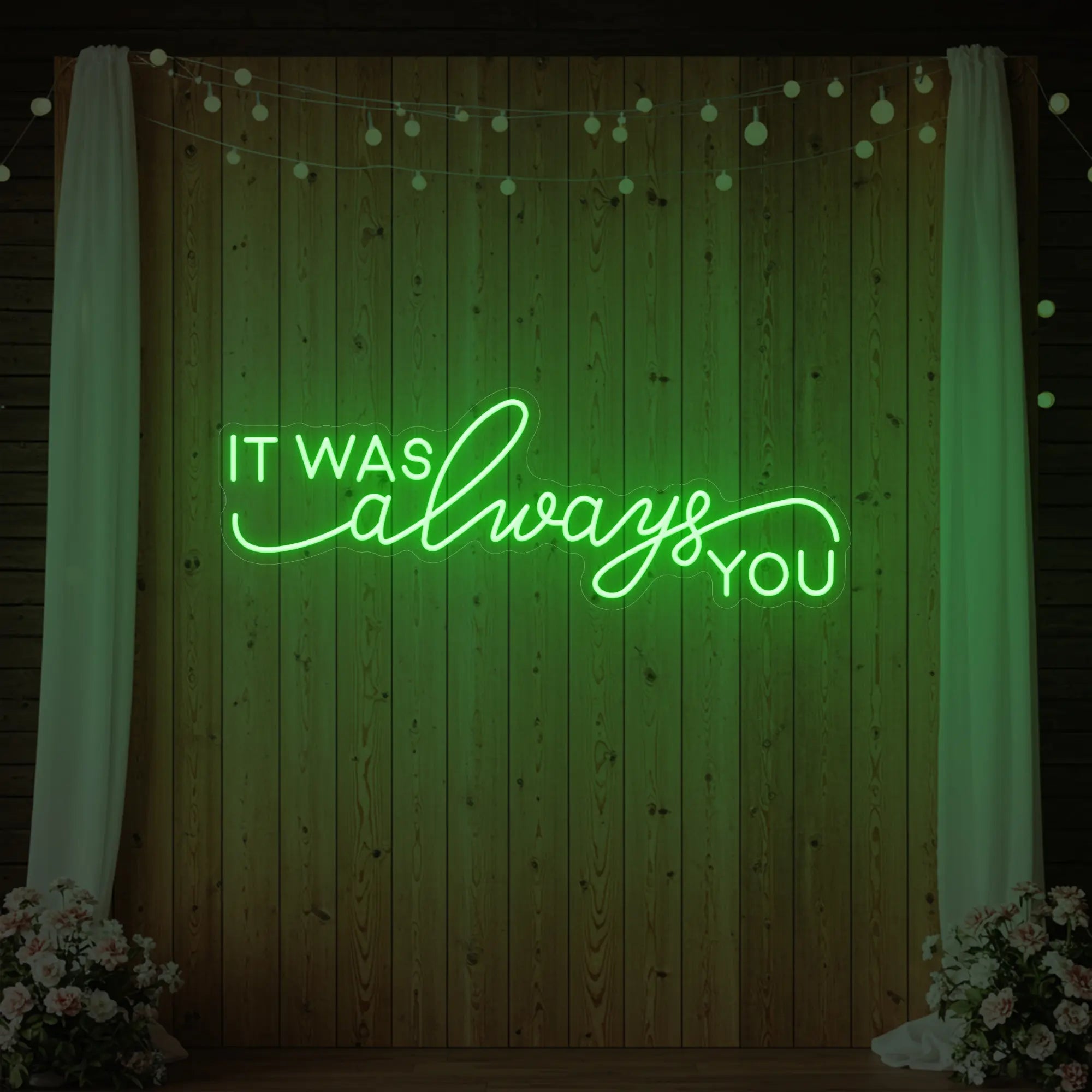 Photo of the 'It Was Always You' neon sign glowing in green against a styled interior wall.