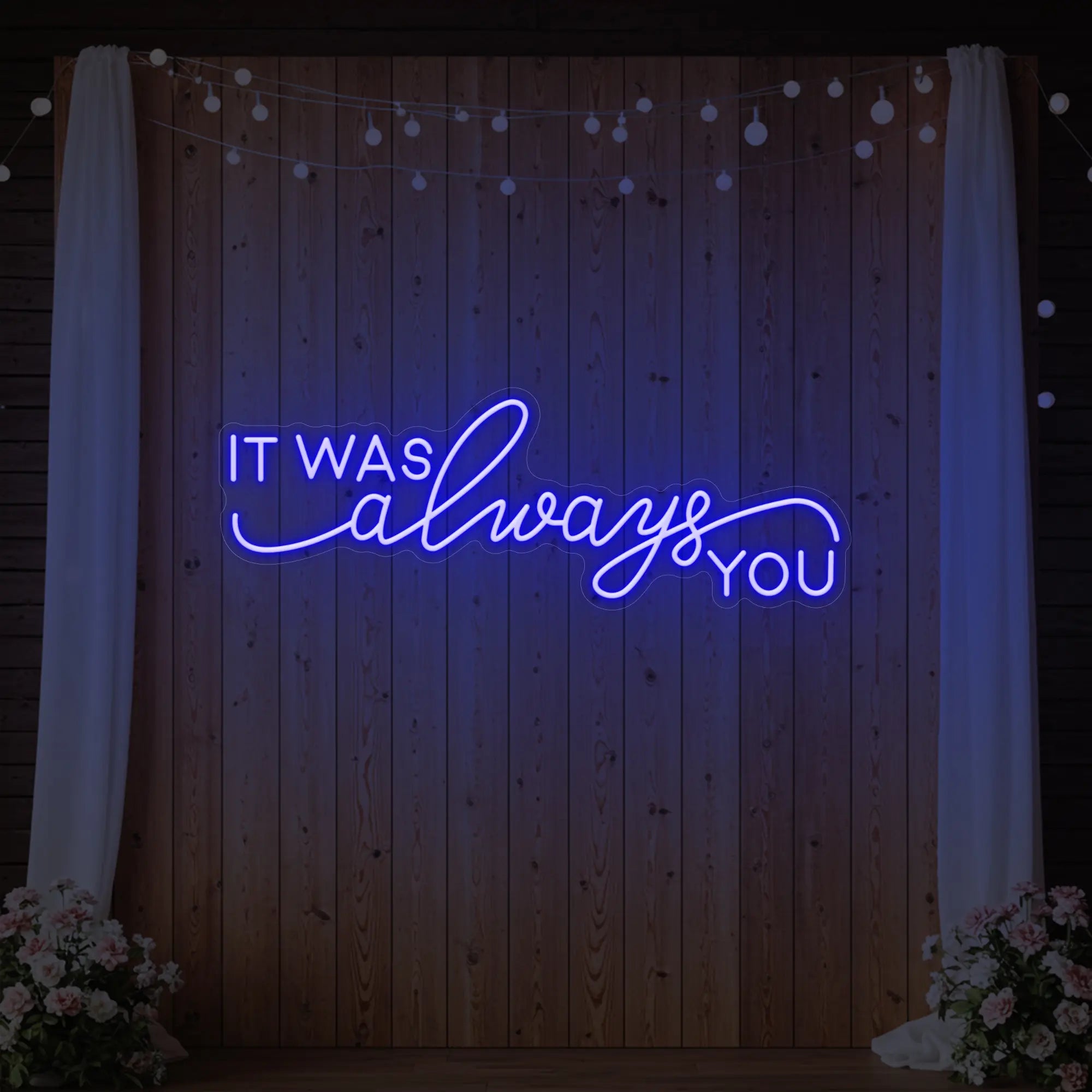 Photo of the 'It Was Always You' neon sign glowing in deep blue against a styled interior wall.