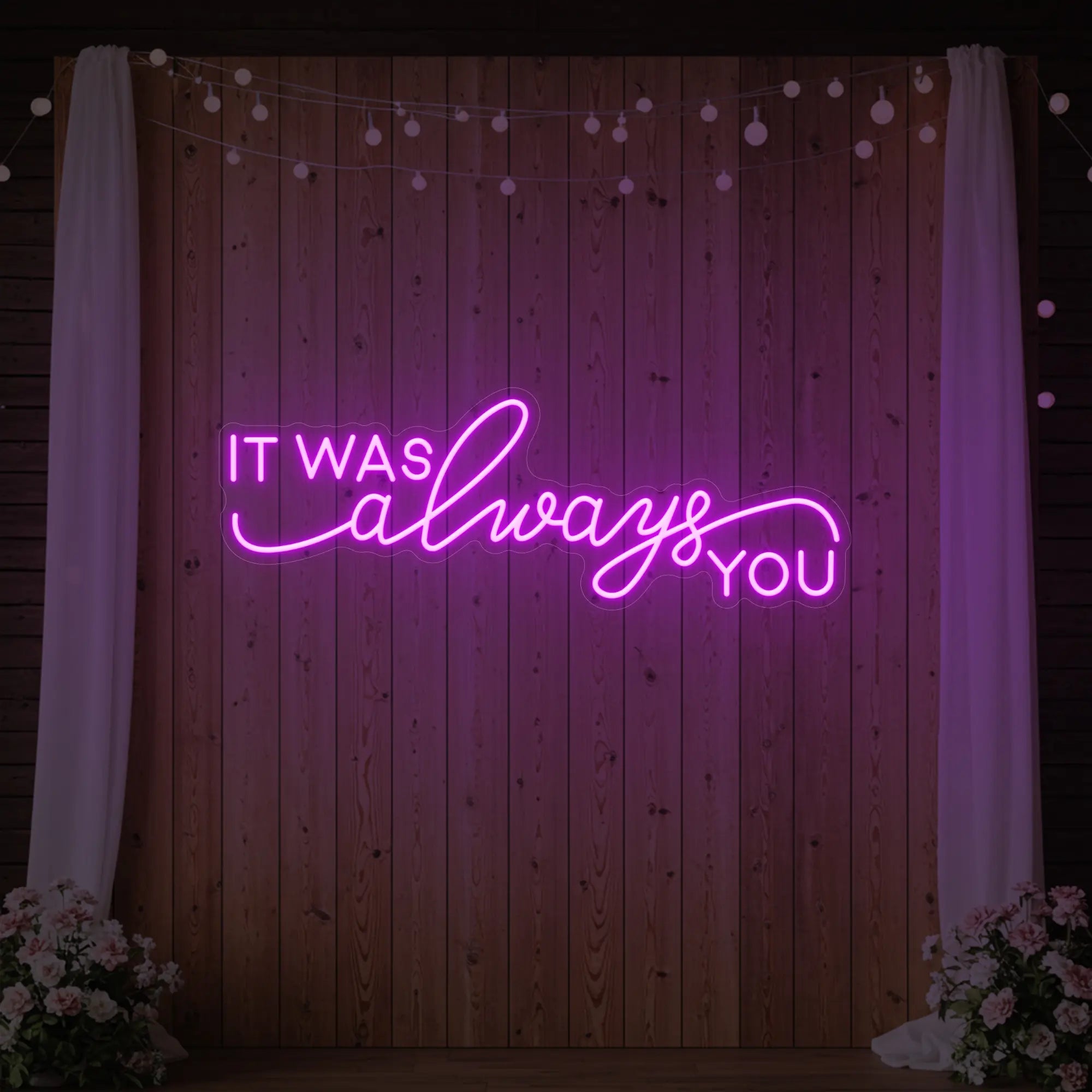 Photo of the 'It Was Always You' neon sign glowing in deep pink against a styled interior wall.