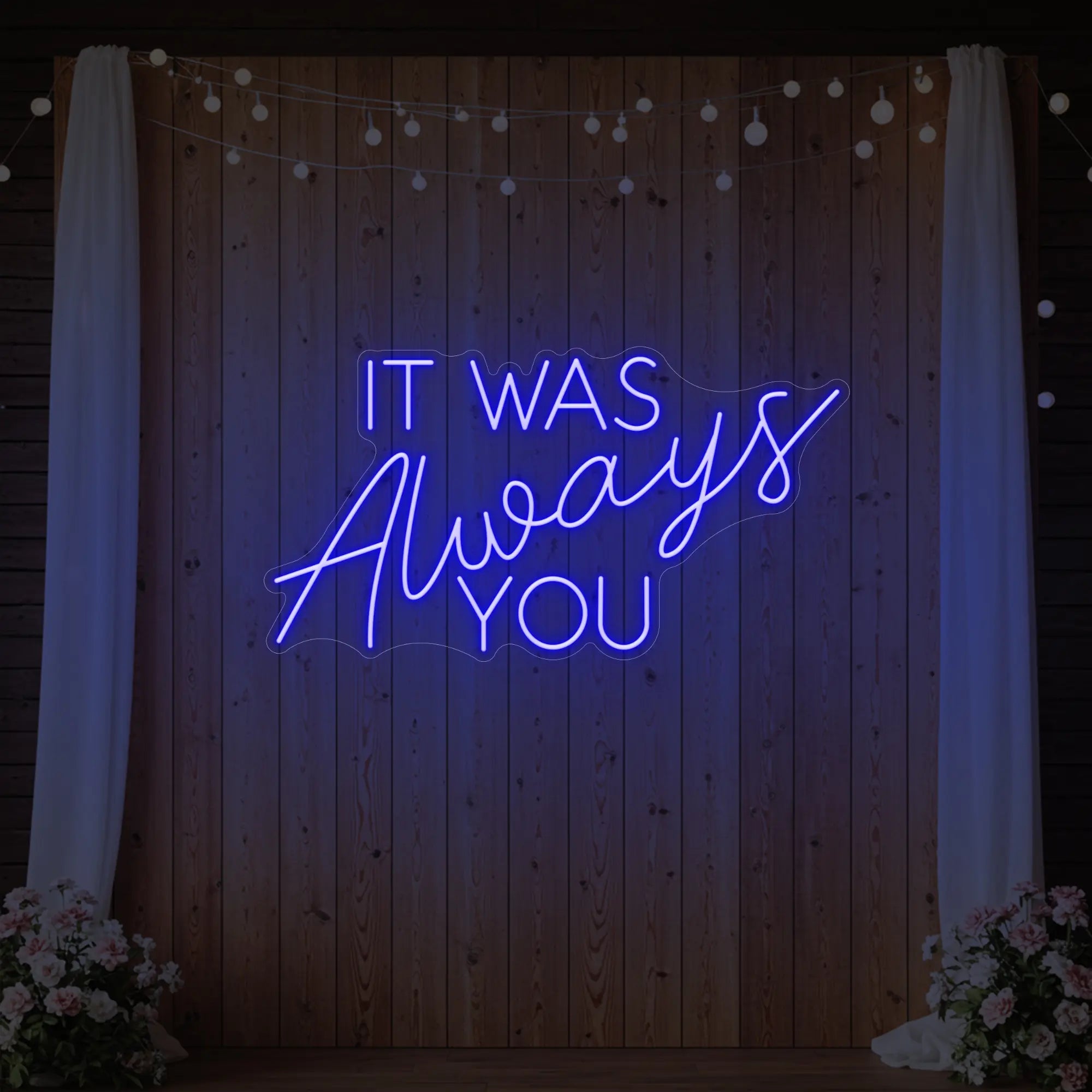 Photo of the 'It Was Always You' neon sign glowing in deep blue against a styled interior wall.