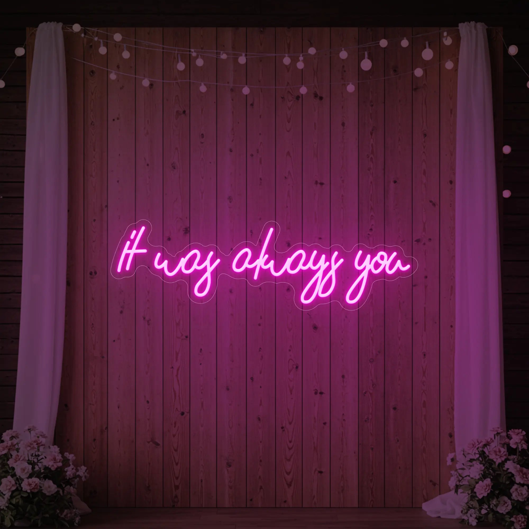 Photo of the 'It Was Always You' neon sign glowing in light pink against a styled interior wall.
