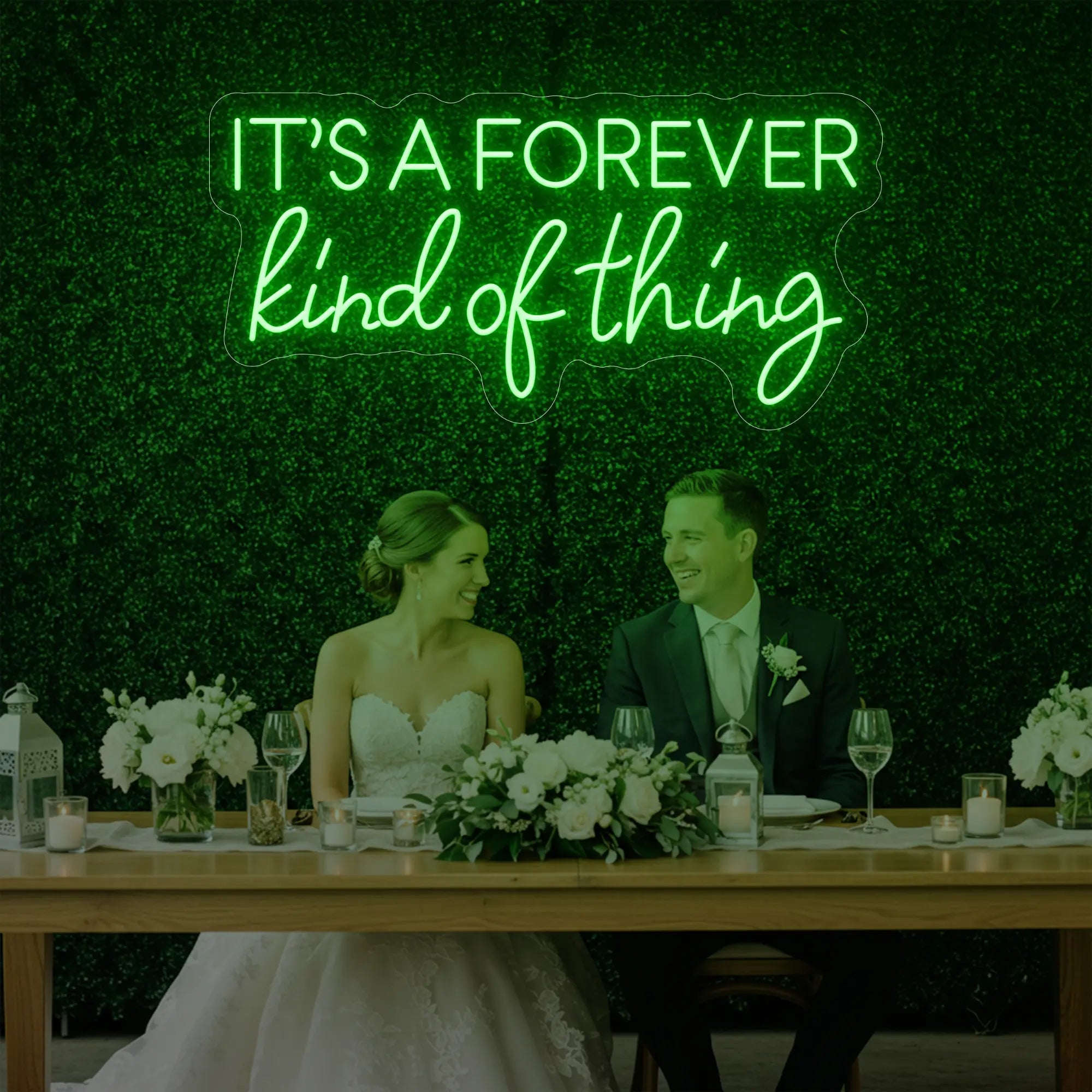 Photo of the 'It’s a Forever Kind of Thing' neon sign glowing in green against a styled interior wall.