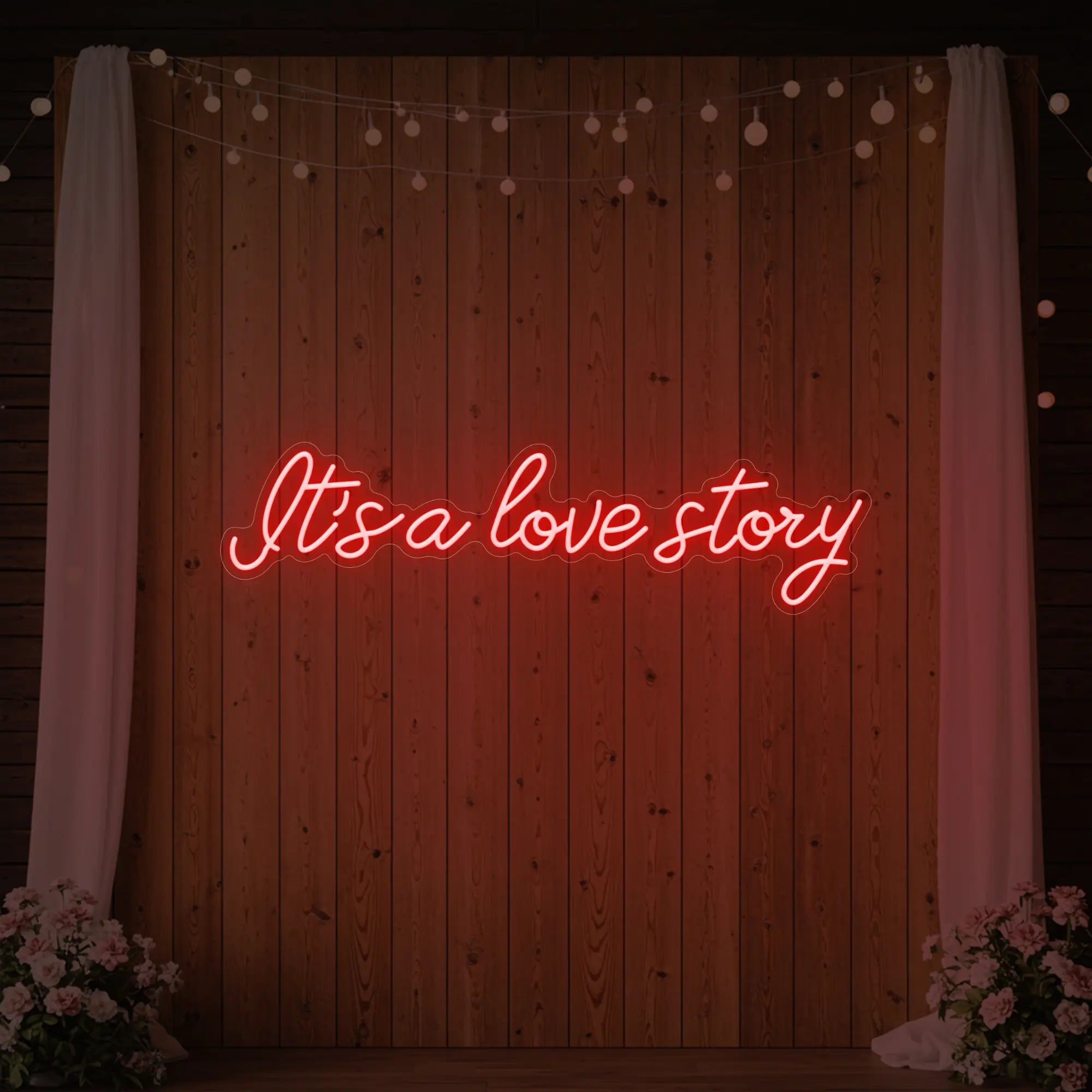 Photo of the 'It’s a Love Story' neon sign glowing in red against a styled interior wall.