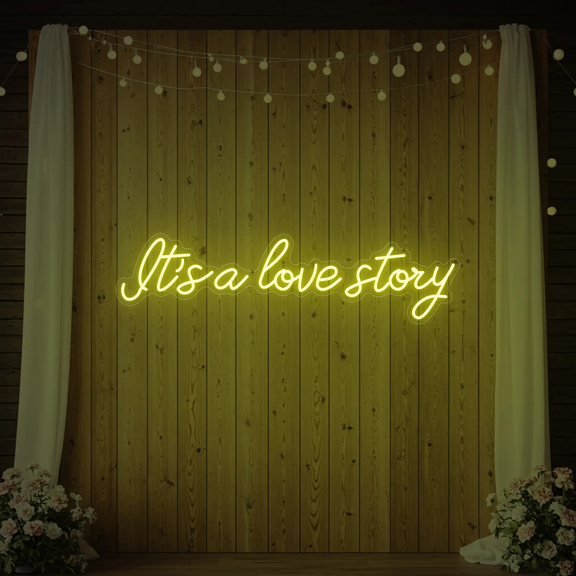 Photo of the 'It’s a Love Story' neon sign glowing in lemon yellow against a styled interior wall.