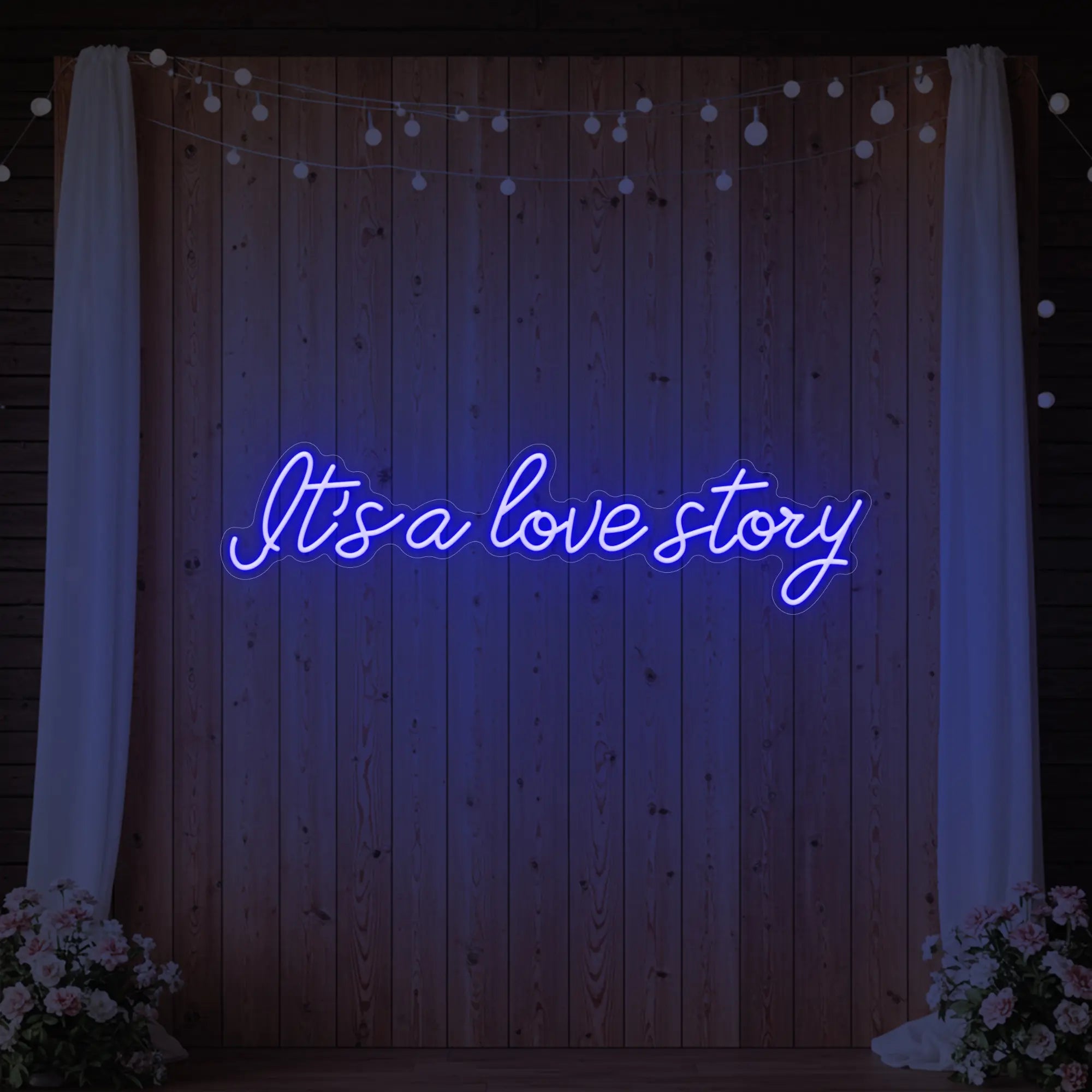 Photo of the 'It’s a Love Story' neon sign glowing in deep blue against a styled interior wall.