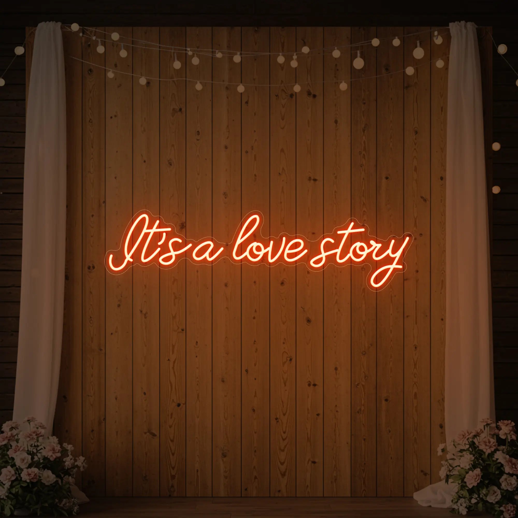 Photo of the 'It’s a Love Story' neon sign glowing in golden yellow against a styled interior wall.