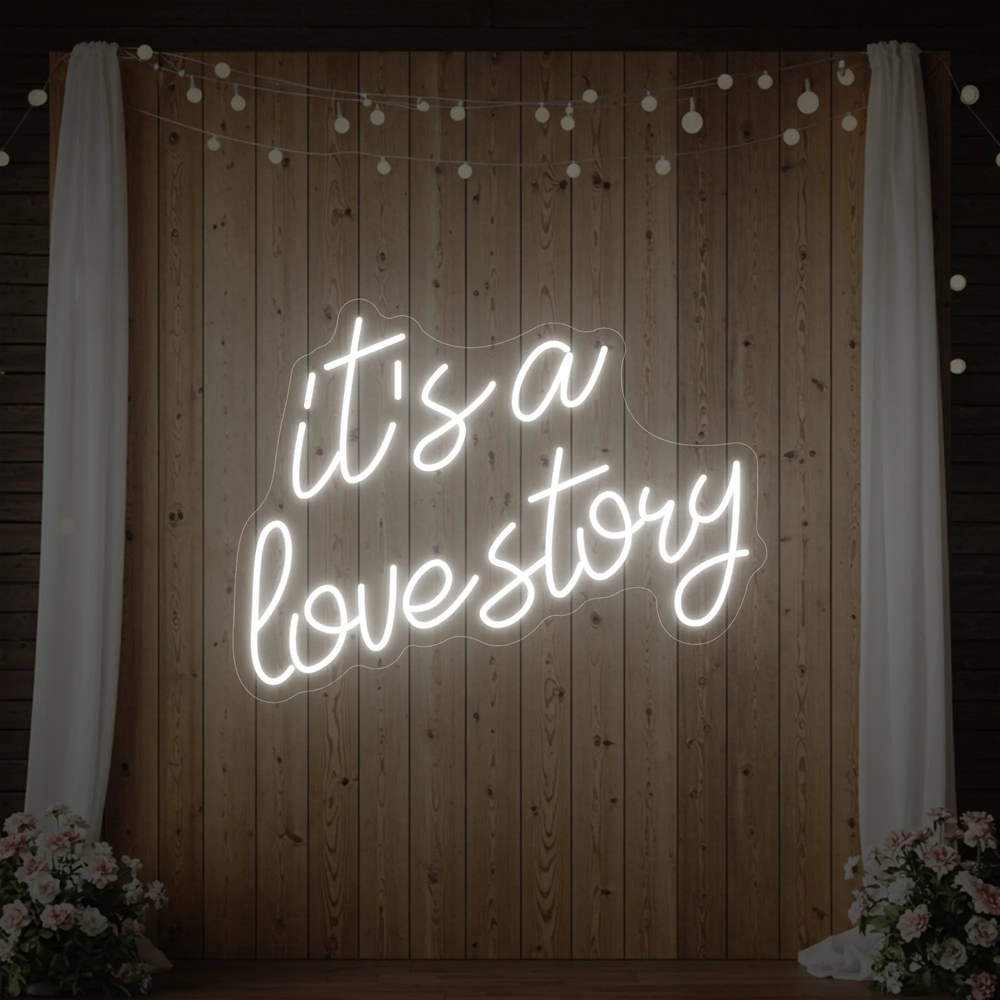 Photo of the 'It’s a Love Story' neon sign glowing in cool white against a styled interior wall.