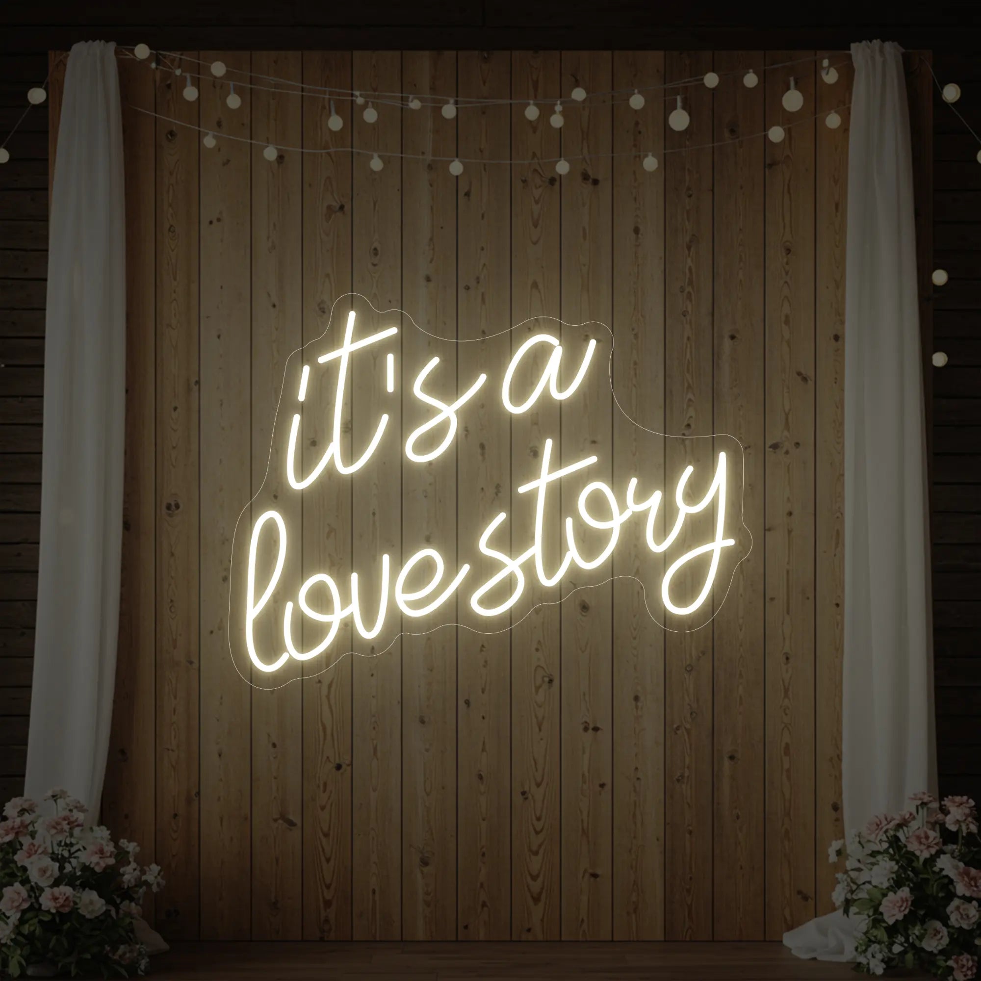 Photo of the 'It’s a Love Story' neon sign glowing in warm white against a styled interior wall.