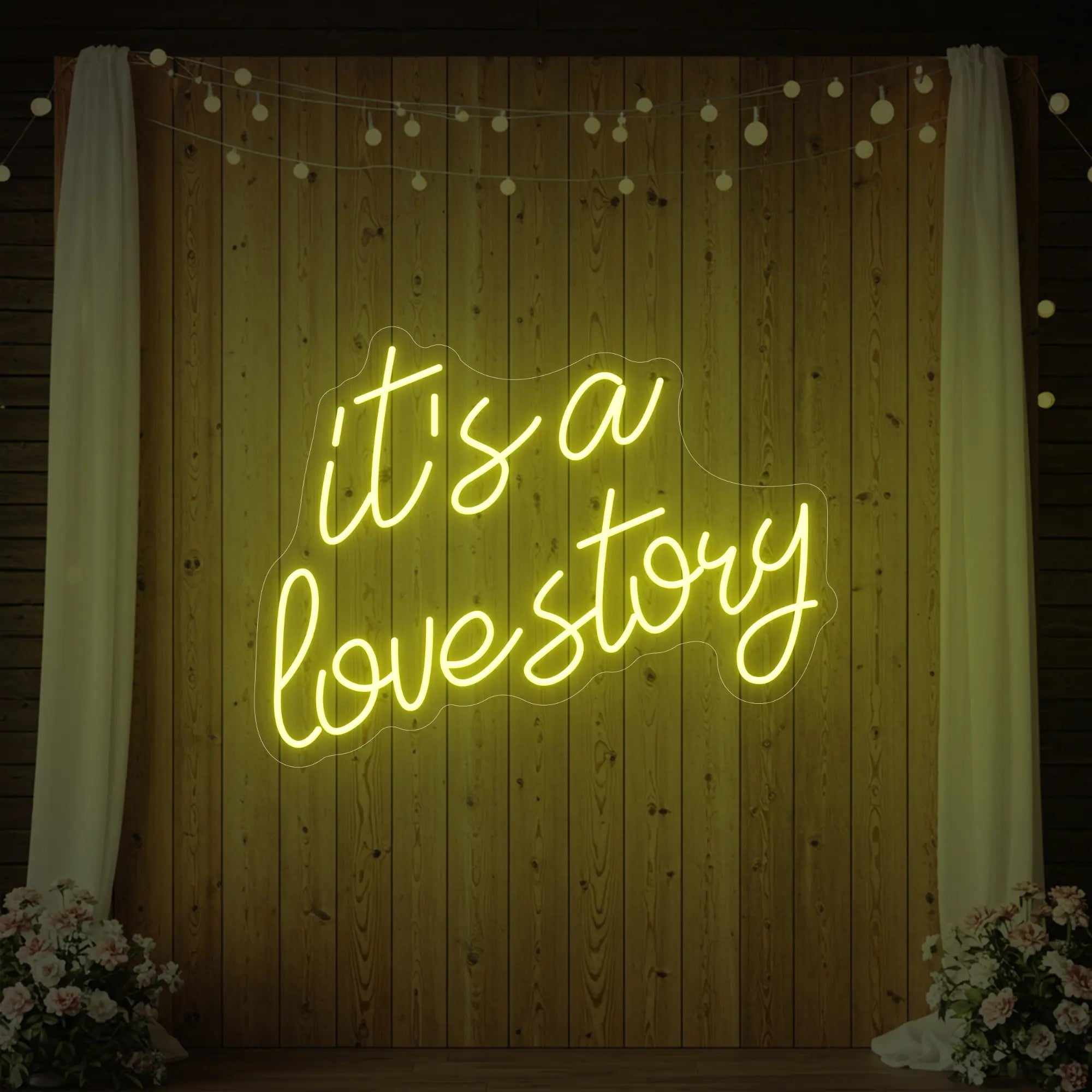 Photo of the 'It’s a Love Story' neon sign glowing in lemon yellow against a styled interior wall.